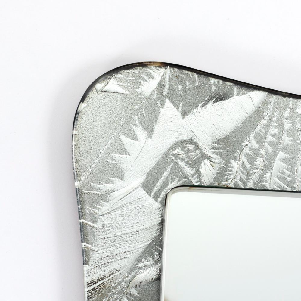 Italian Mid-Century Wall-Mirror with Abstract Silver Leaf Decoration 1970s

Refined Italian mid-century mirror with wavy outer edge.
The lower mirror glass was partially roughened before it was silvered, creating a matt and shiny decor with highs