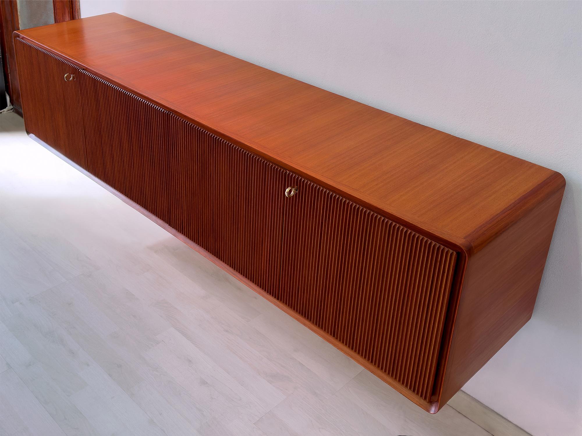 This magnificent Italian Sideboard in teak wood is a stunning example of the exceptional craftsmanship produced by the Consorzio Esposizione Mobili Cantù in the 1950s.
Founded in 1949, the consortium aimed to bring together the best of Canturina