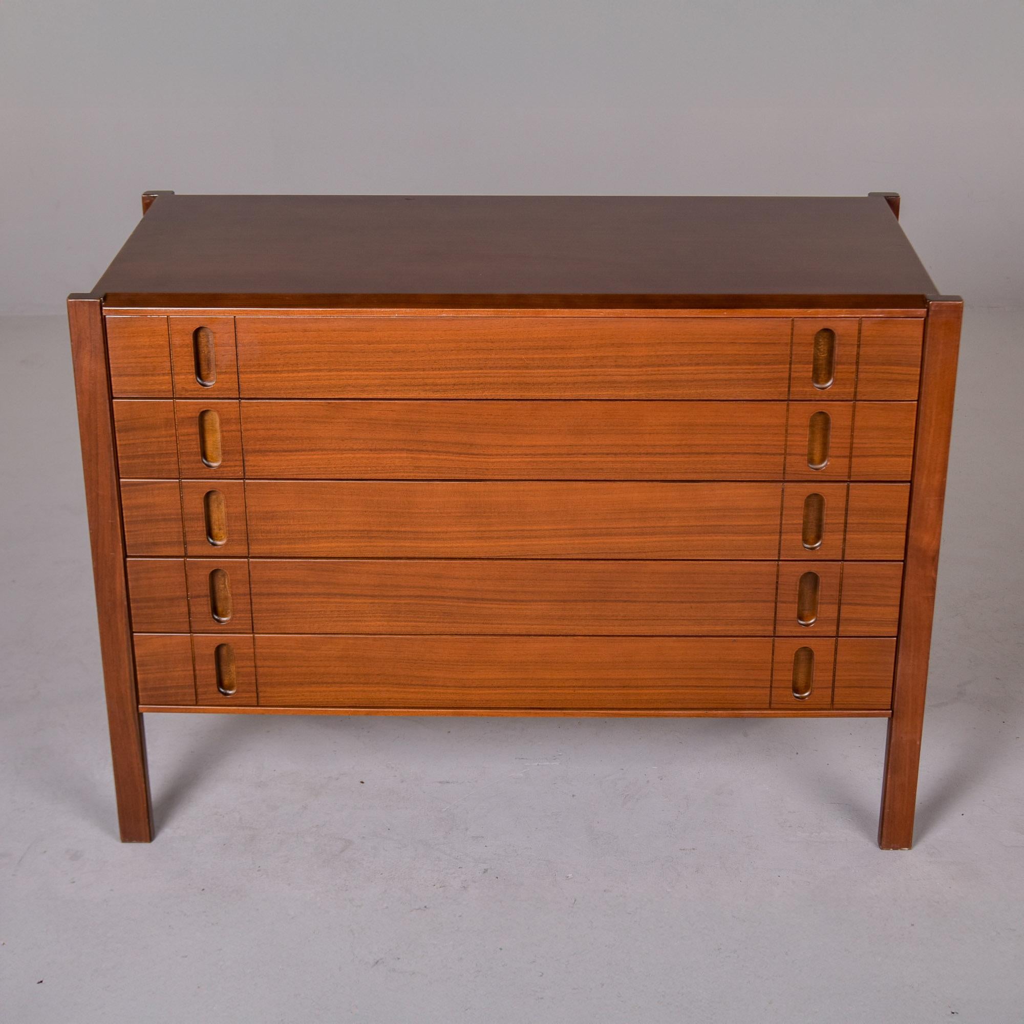 Diese vielseitige Kommode wurde in Italien gefunden und stammt aus den 1960er Jahren. Diese Kommode aus Nussbaumholz besticht durch ihr elegantes Design und ihre Proportionen mit fünf schlanken Schubladen und geschnitzten Griffeinsätzen. Gerade,