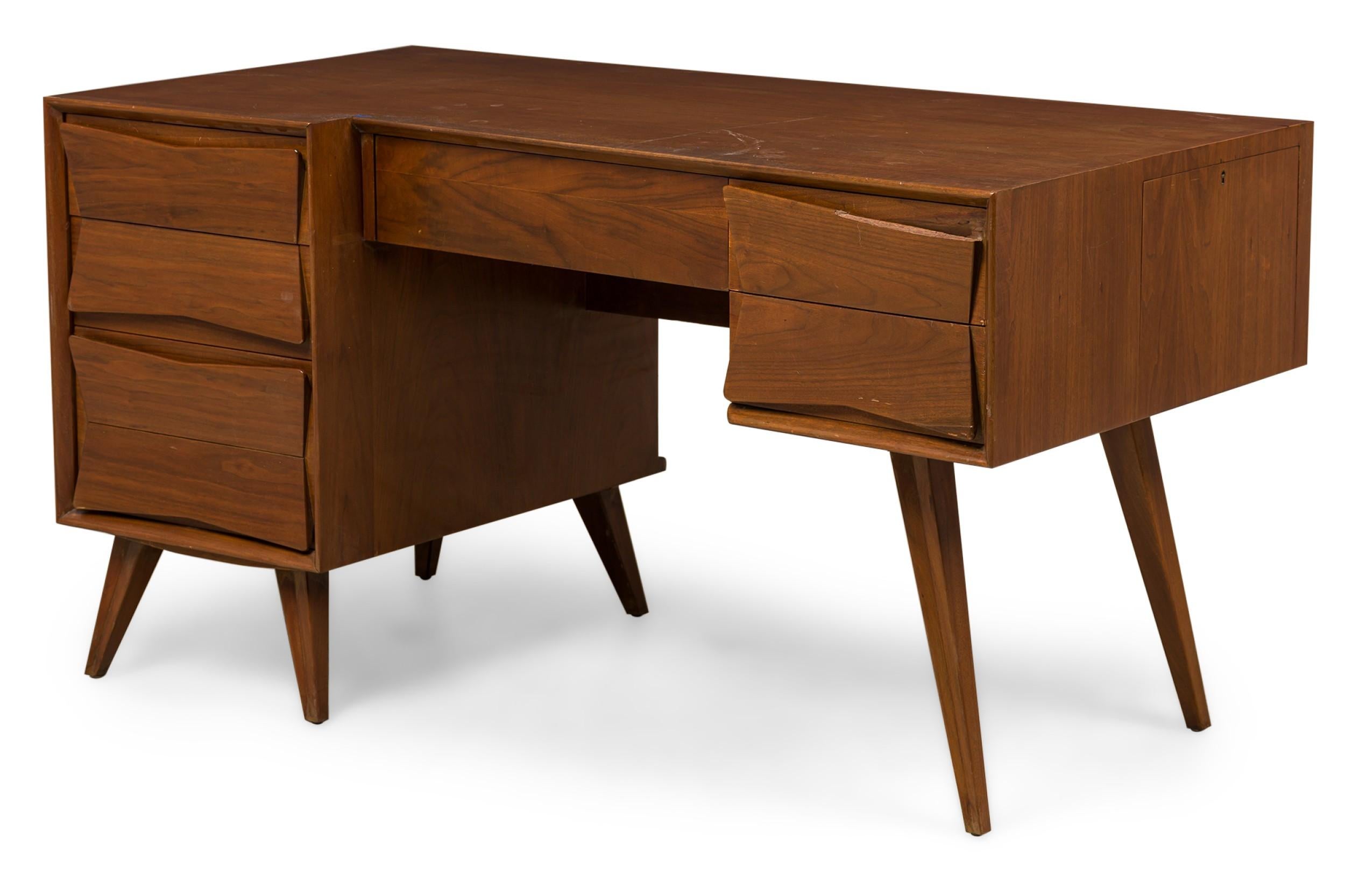 Italian Mid-Century walnut desk with a centere drawer flanked by 2 shaped front drawers on the right and 3 on the left suppoted on angled legs (style of GIO PONTI)

