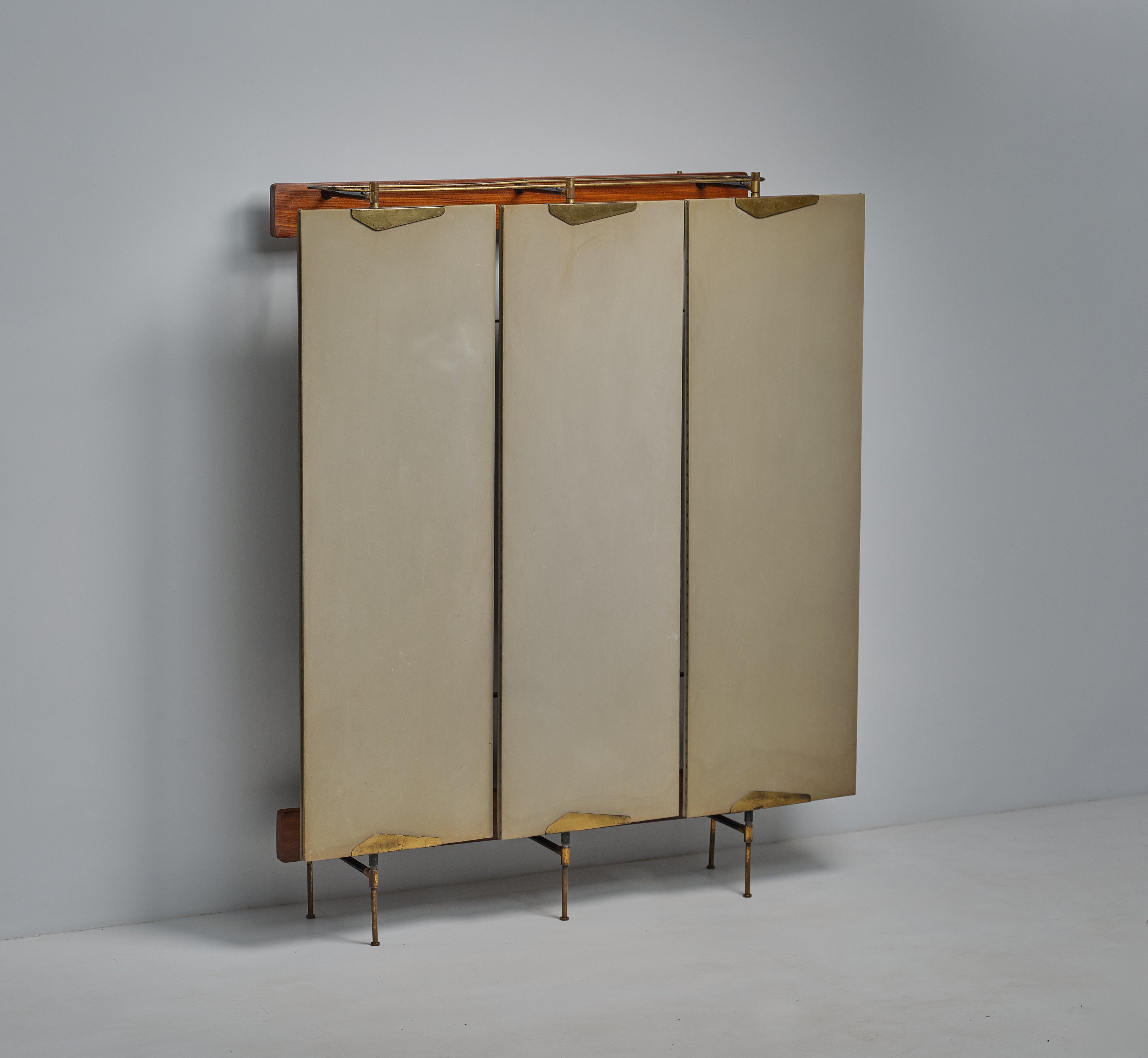 Introducing a masterpiece of Italian craftsmanship from the high-end production of the 1950s: a stunning wardrobe that seamlessly combines modern design with a light and airy aesthetic. This exceptional piece features three swiveling doors with a