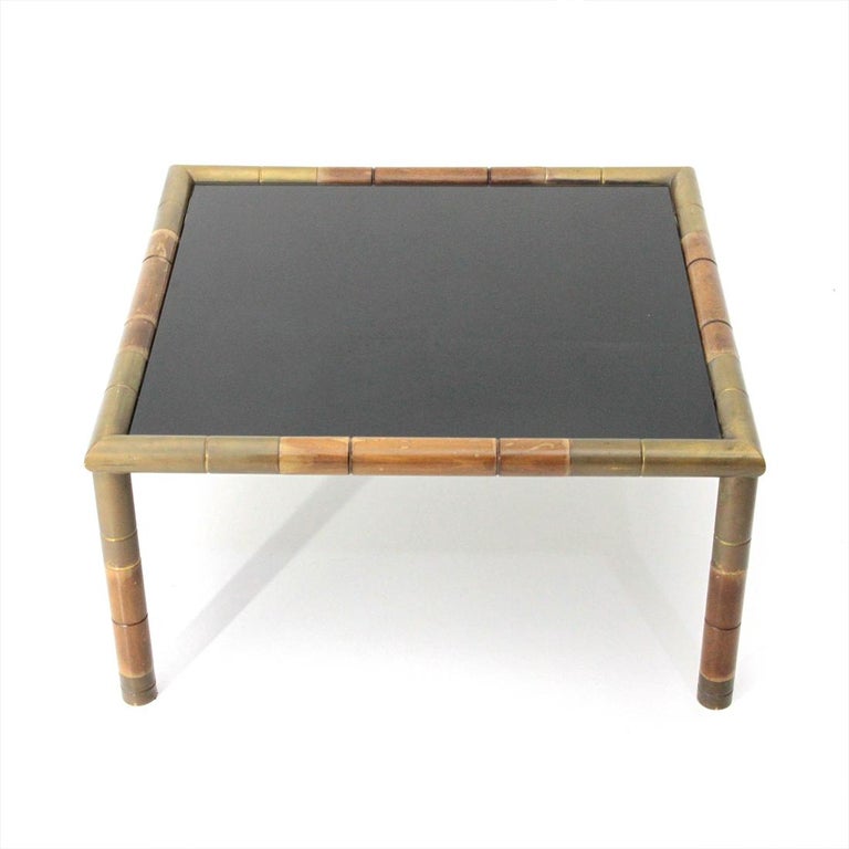 Italian-made coffee table produced in the 1970s.
Solid wood structure with bamboo effect.
Corners and feet in brass.
Black glass top.
Good general condition, some marks and halos due to normal use over time.

Dimensions: Length 70 cm, depth 70