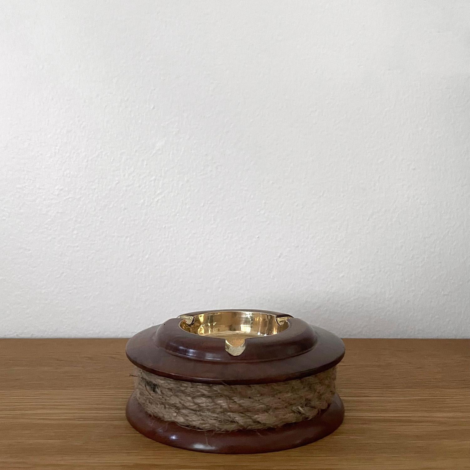 Italian wood & brass ashtray
Italy, circa 1950s
This charming piece will be a great addition to any surface
Twisted rope band encompasses the sculpted wood & aged brass ashtray
Light surface markings 
Patina from age and use 
This listing is for a