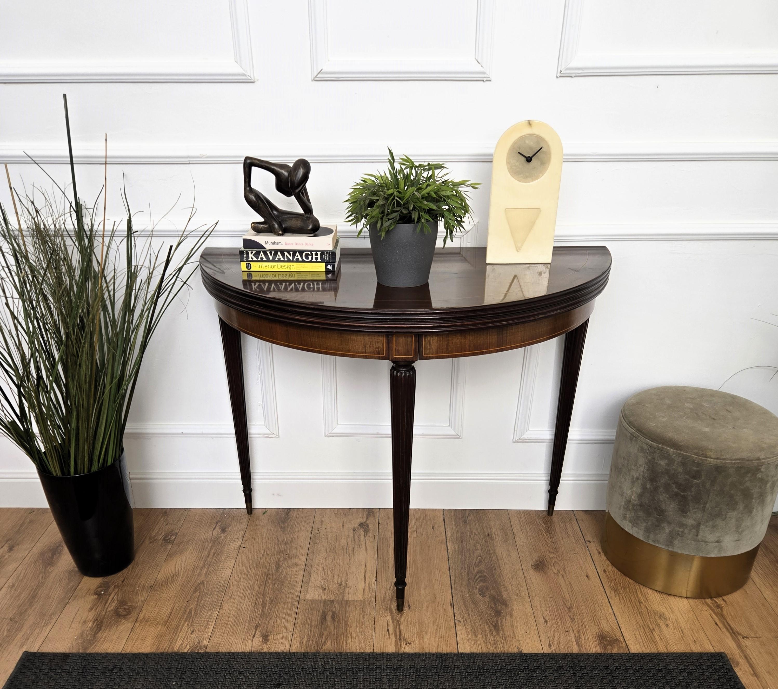 Mesa redonda plegable demi-lune, muy elegante y encantadora, que puede utilizarse como mesa consola y transformarse en mesa de comedor o de juegos. La parte superior de madera está decorada y enmarcada en dorado por ambos lados, al igual que la