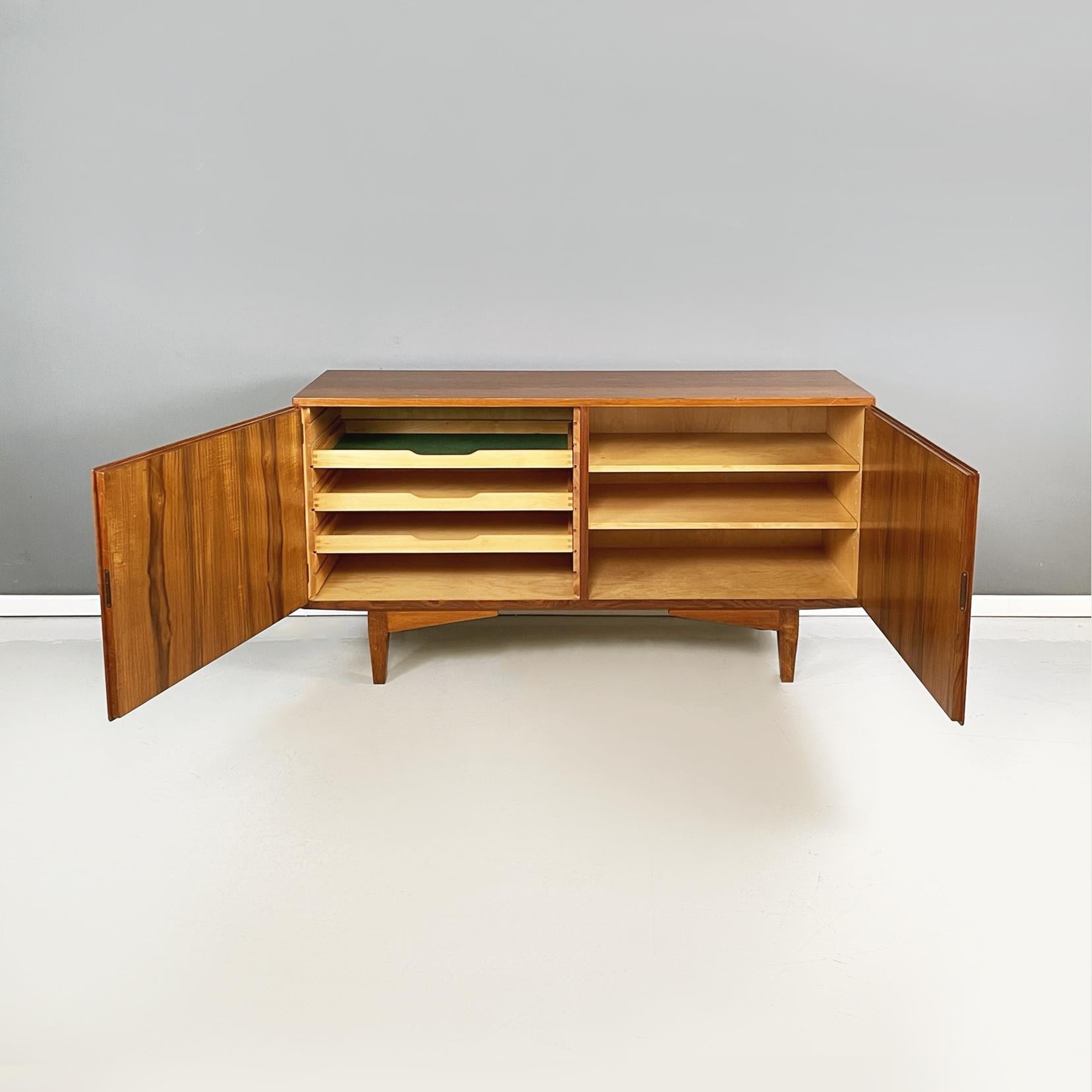 Italian midcentury Wooden sideboard with drawer and shelves, 1960s
The rectangular sideboard is in solid wood. On the front it has two hinged doors, inside on one side there are 3 drawers and on the other 2 shelves. The doors lock with a key. Legs