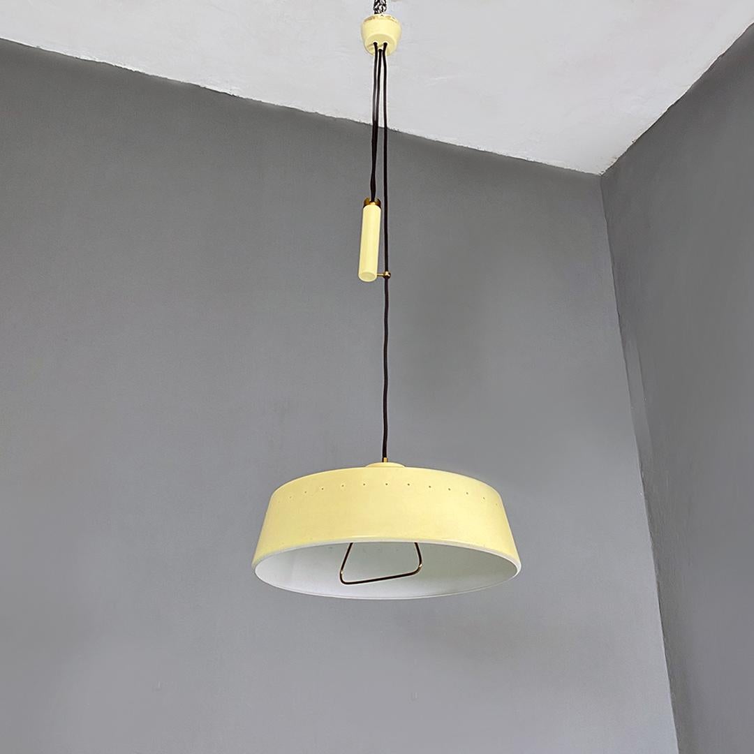 Italian mid century modern light yellow metal and brass chandelier with up and down method, 1960s.
Chandelier with circular base lampshade, in light yellow metal with small holes along the entire perimeter and with handle inside the brass rod