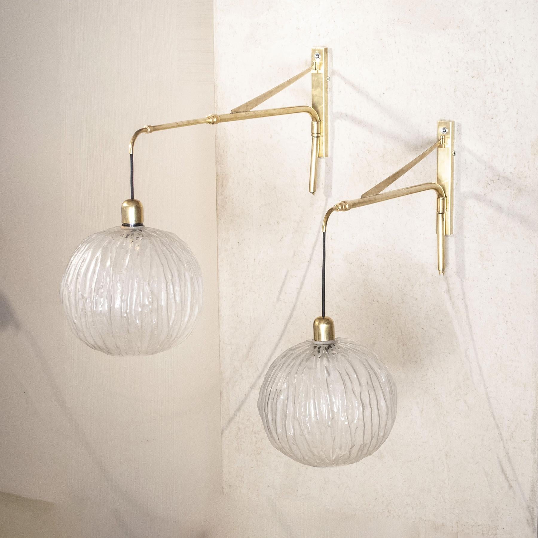 Pair of large 60's arm wall lights of rare elegance composed of a 180 ° adjustable telescopic brass structure with pumpkin-shaped spheres in finely worked glass.

Dimensions:
Minimum lamp center depth 60 cm from the wall maximum 120 cm, height shown