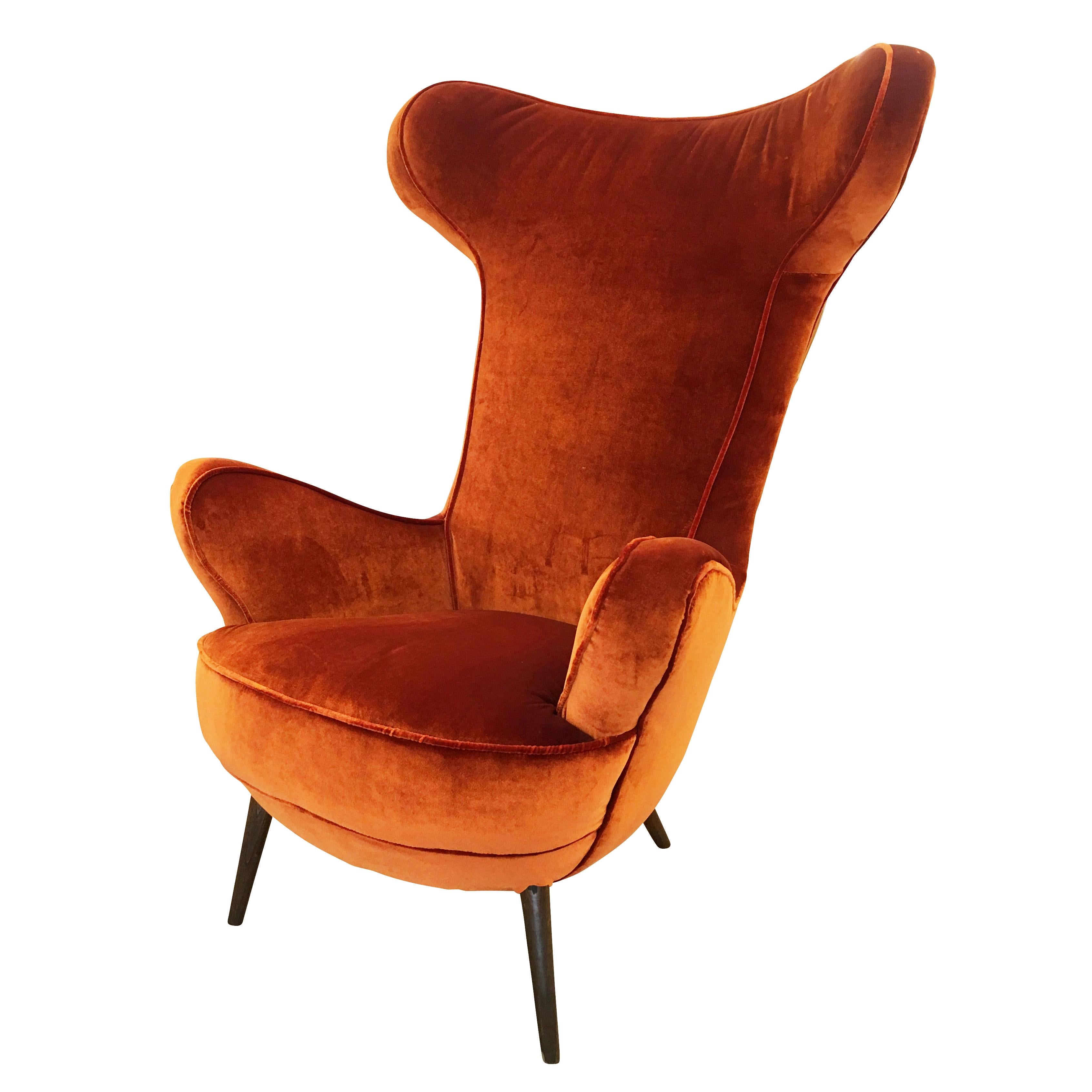 Sculptural Italian lounge chair in the style of Carlo Mollino. Features a high back with rounded open wings, the armrests continue the same pattern. Elongated wood legs.