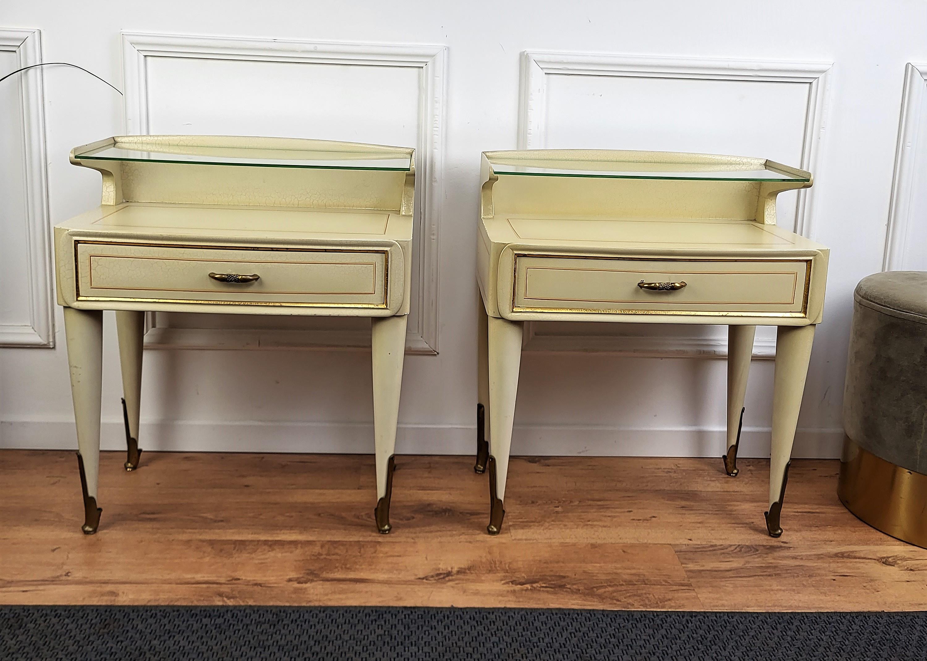 Very elegant and refined Italian 1950s Mid-Century Modern pair of bed side night stands tables in white painted wood with front drawer and second glass top with brass details such as the handles and the 4 fluted legs finials. Those nightstands make