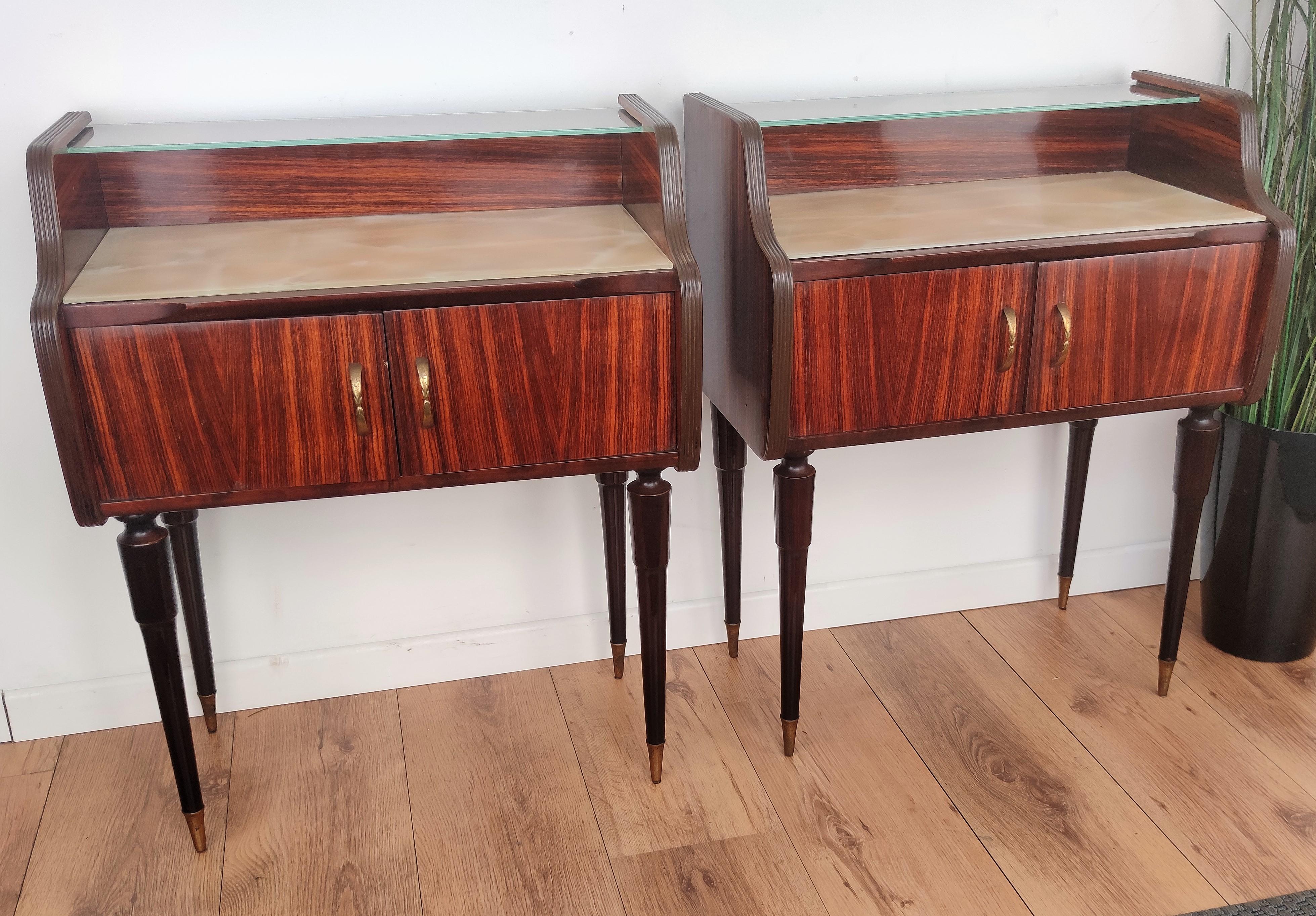 Very elegant and refined Italian 1950s Mid-Century Modern pair of bed side night stands tables in walnut veneer wood with double front door, lacquered glass and second glass top with brass details such as the handles and the 4 fluted legs finials.