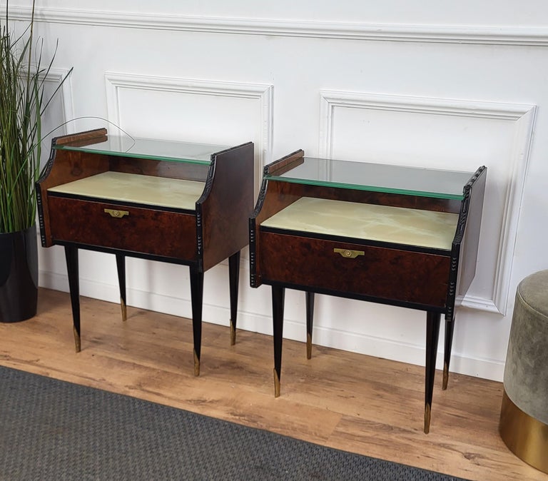 Very elegant and refined Italian 1950s Mid-Century Modern pair of bed side night stands tables in walnut veneer wood with front flip door, lacquered glass and second glass top with brass details such as the handles and the 4 fluted legs finials.