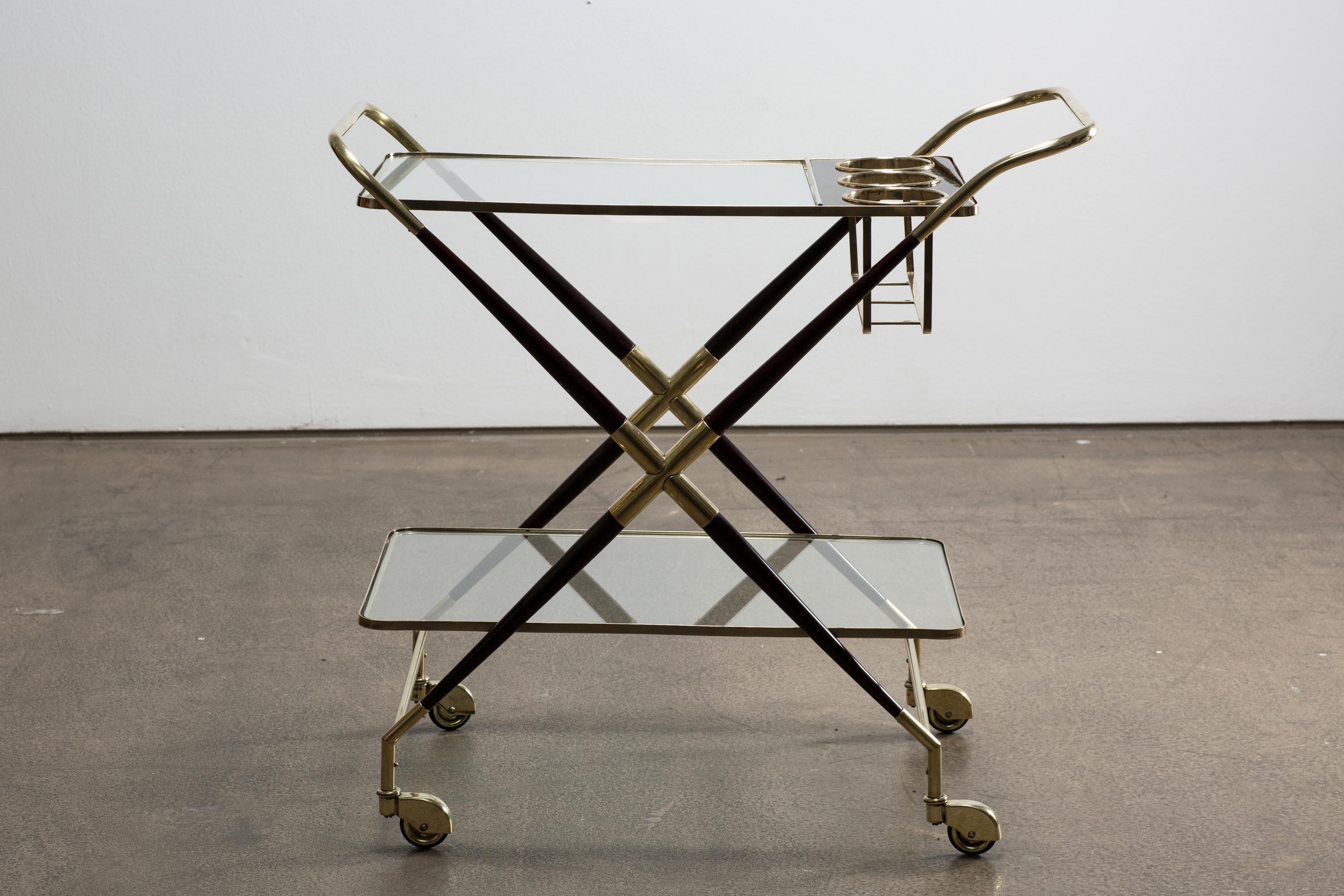 A very beautiful Italian Mid-Century bar cart designed by Cesare Lacca, circa 1940.
This well-crafted piece is made of brass and black wood which is polished with shellac. Its structure has two dimensions with glass shelves and three bottle holders