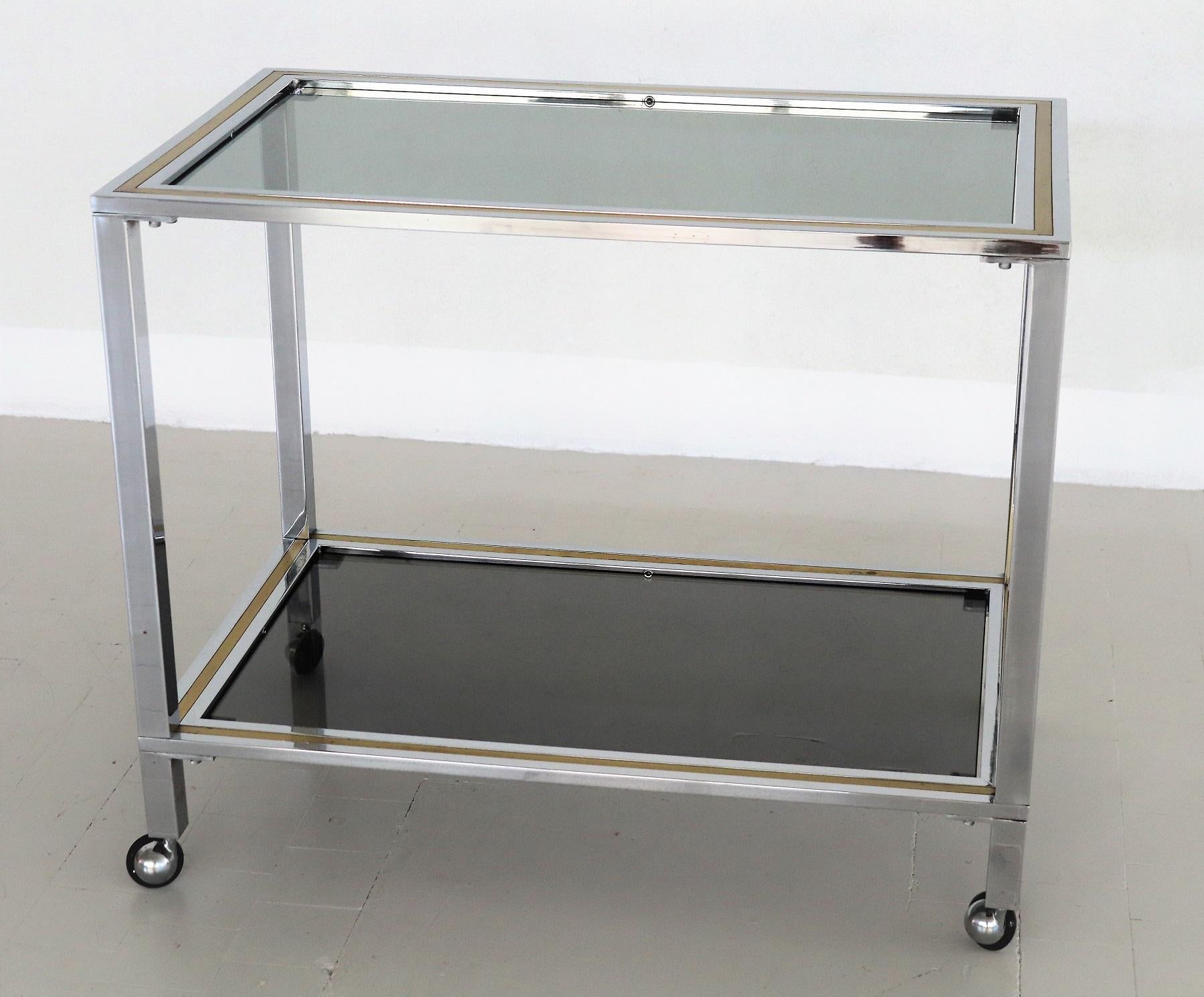 Beautiful bar cart or trolley made in Italy in the 1970s, in the style of Romeo Rega.
The trolley is made of shiny chrome and brass, and has two smoked glasses in grey - green.
New rollers in the 1970s style, therefore excellent moving.
Very good