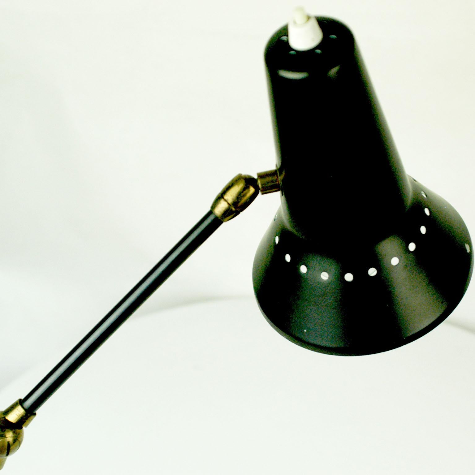 Cette charmante lampe de bureau ou de table à pince en laiton des années 1950 avec abat-jour réglable et perforé laqué noir a été fabriquée par Stilnovo dans les années 1950. La lampe dispose de deux liens supplémentaires, ce qui permet de l'ajuster