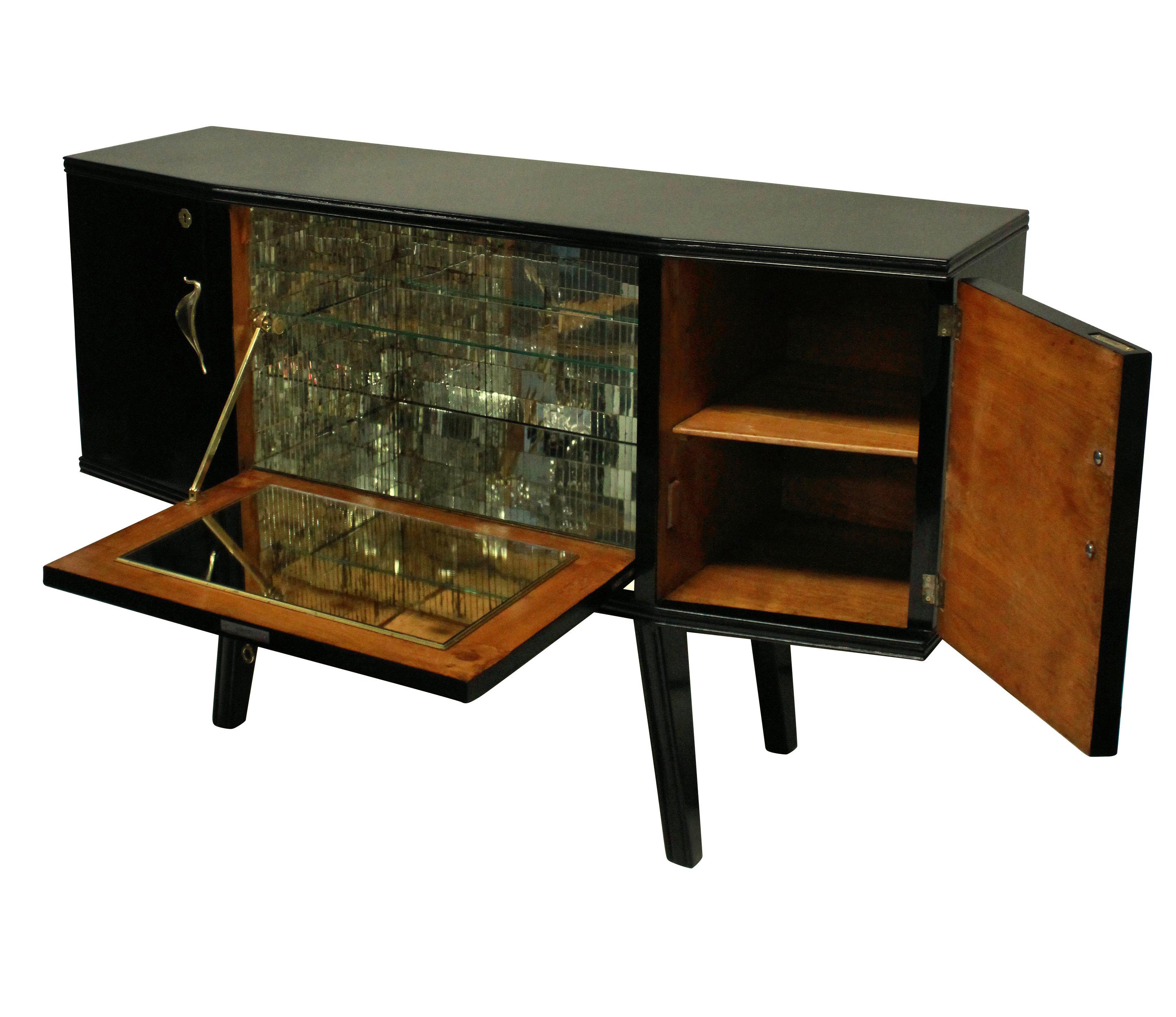 A stylish Italian bar credenza of interesting angular design in black lacquer with sepele wood interior, with brass hardware and a faux malachite central panel and mirrored interior.
 
   