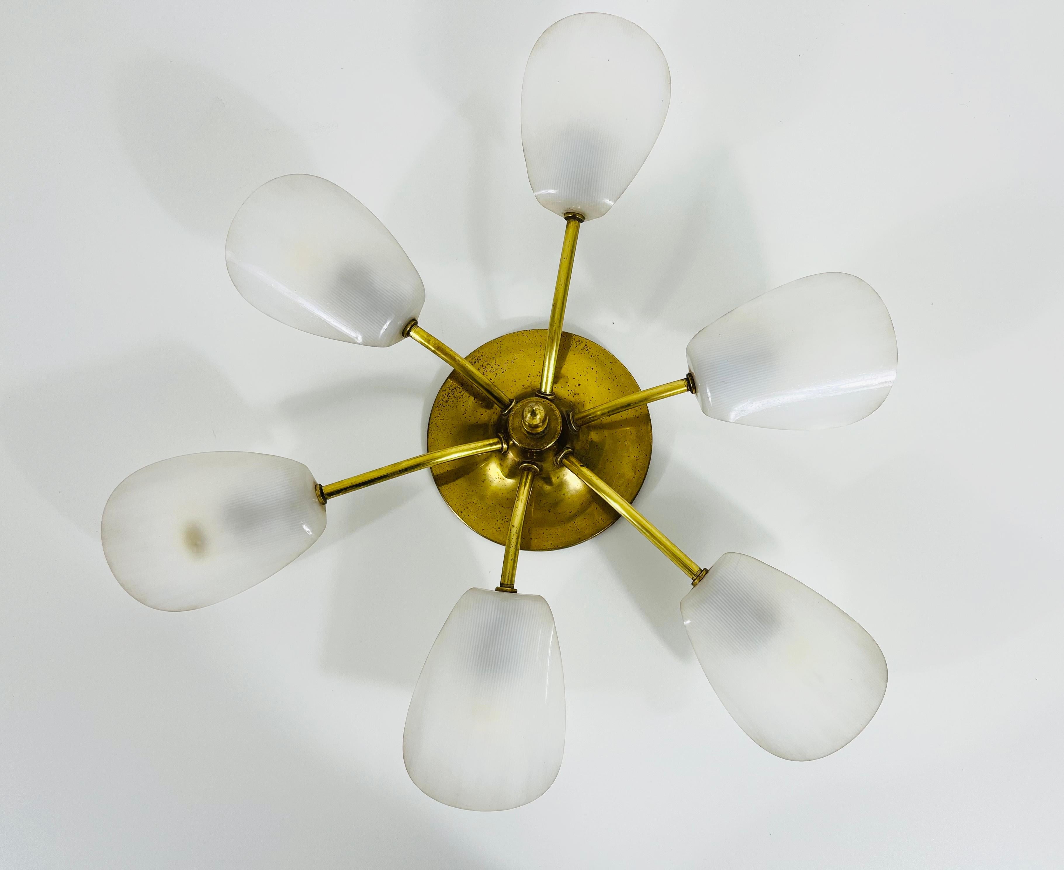 A Sputnik chandelier made in Italy in the 1950s. It is fascinating with its six brass arms with plastic shades, each of it with an E14 light bulb. The shape of the light is similar to a spider.

The light requires 6 E14 light bulbs. Good vintage