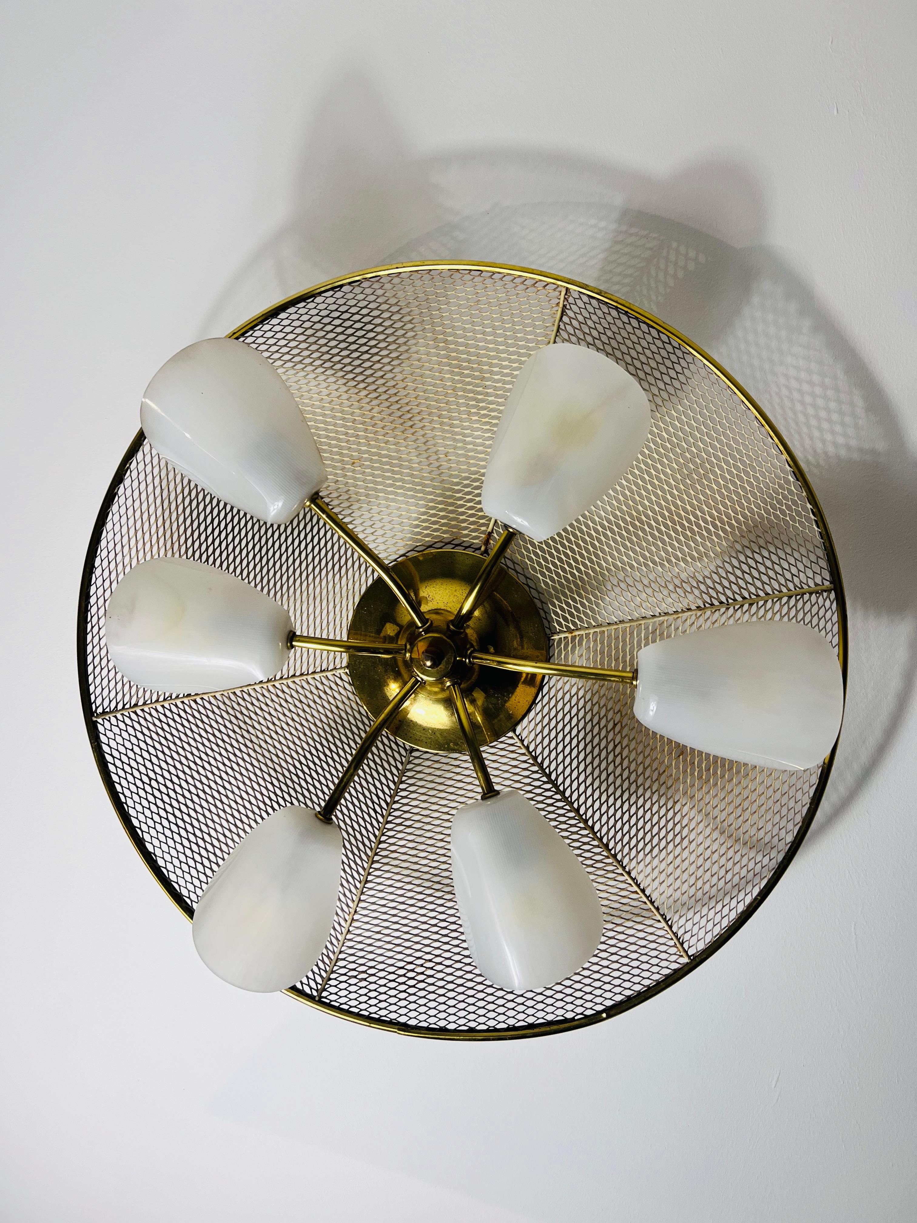This Italian Sputnik ceiling lamp from the 1950s is a striking example of mid-century modern design, inspired by the iconic style of Stilnovo. With its six elegantly curved arms and white acrylic glass shades paired with brass sockets, the lamp