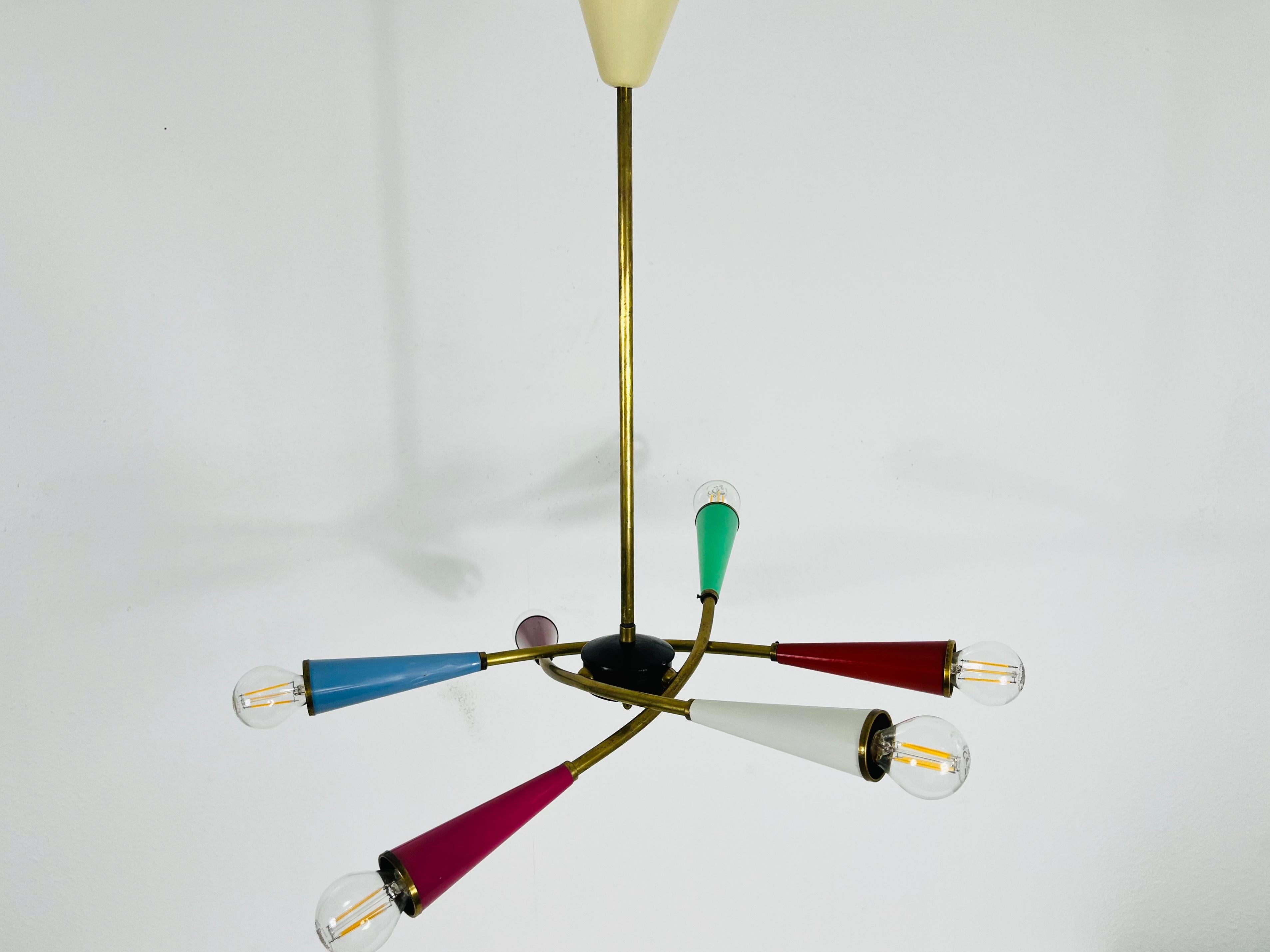 Un coloratissimo lampadario Sputnik attribuito ad Arredoluce e realizzato in Italia negli anni Cinquanta. È affascinante con i suoi sei bracci in ottone, ognuno dei quali contiene una lampadina E14. La forma della luce è simile a quella di un