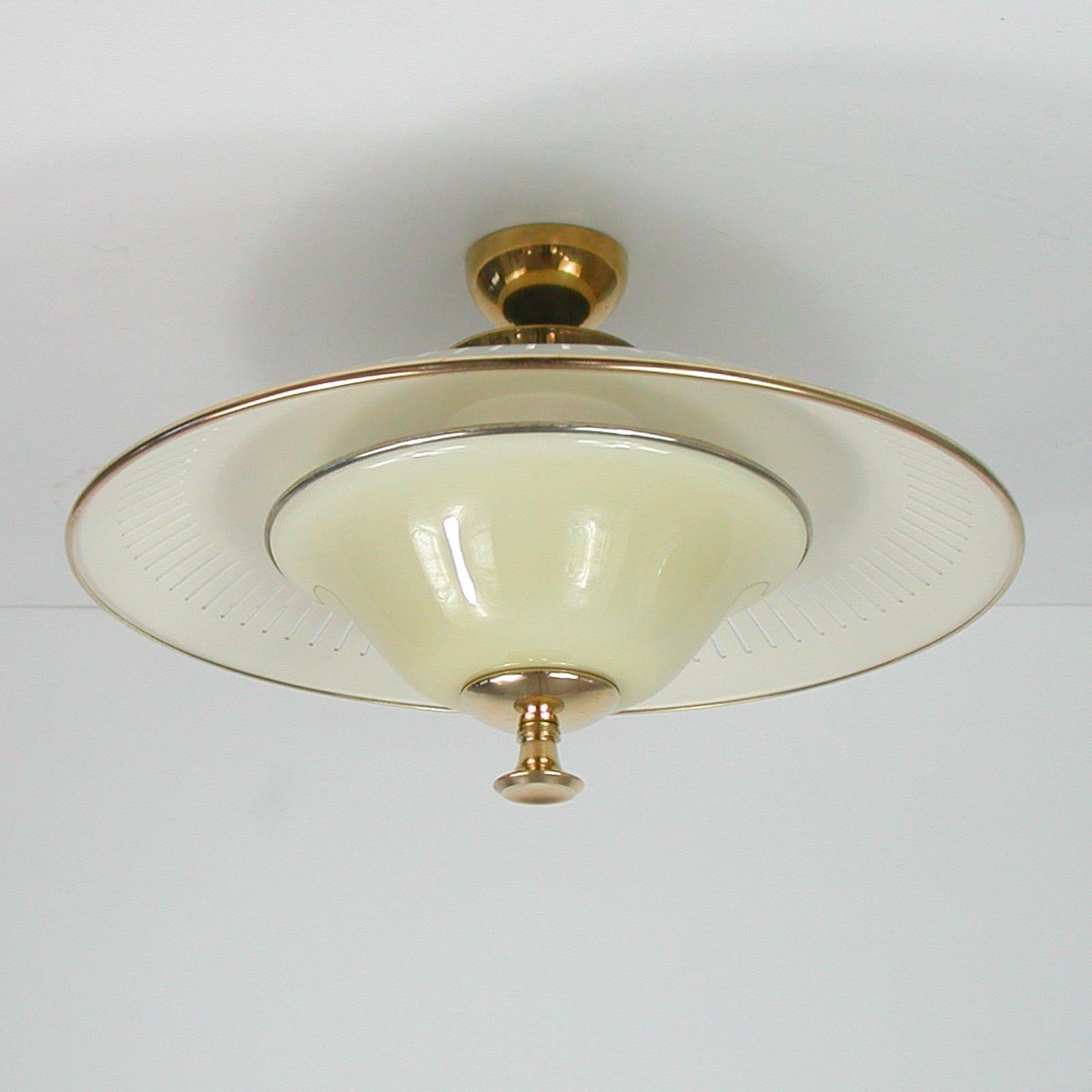 This beautiful midcentury semi flush mount was designed and manufactured in Italy in the 1950s. It features an ivory colored dome shaped lamp shade, a cream colored opaline diffuser and brass hardware.

The lamp has got 2 sockets for E27 bulbs up