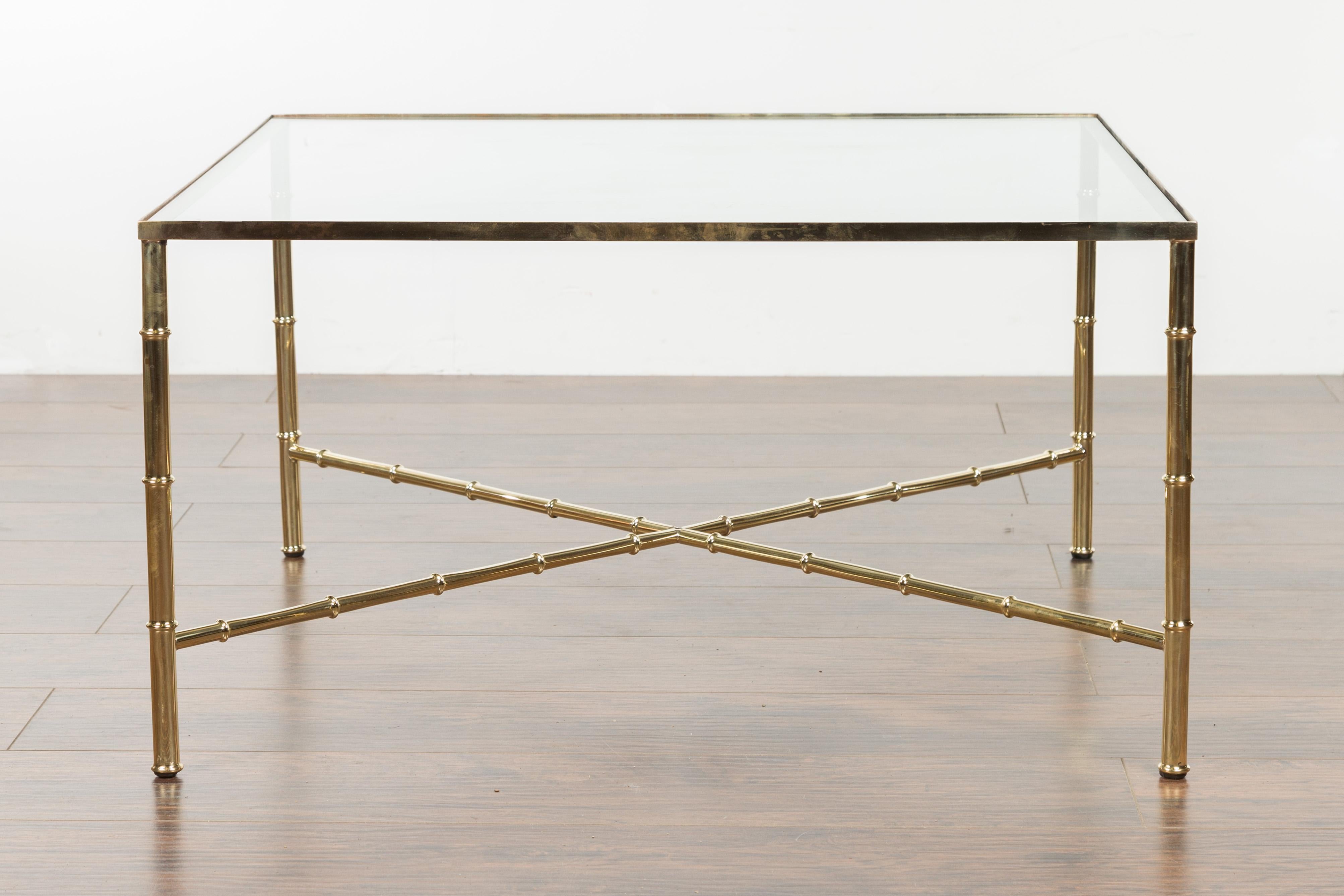 An Italian vintage brass coffee table from the mid-20th century, with glass top. Created in Italy during the midcentury period, this coffee table features a square glass top supported by four straight brass legs connected to one another through an