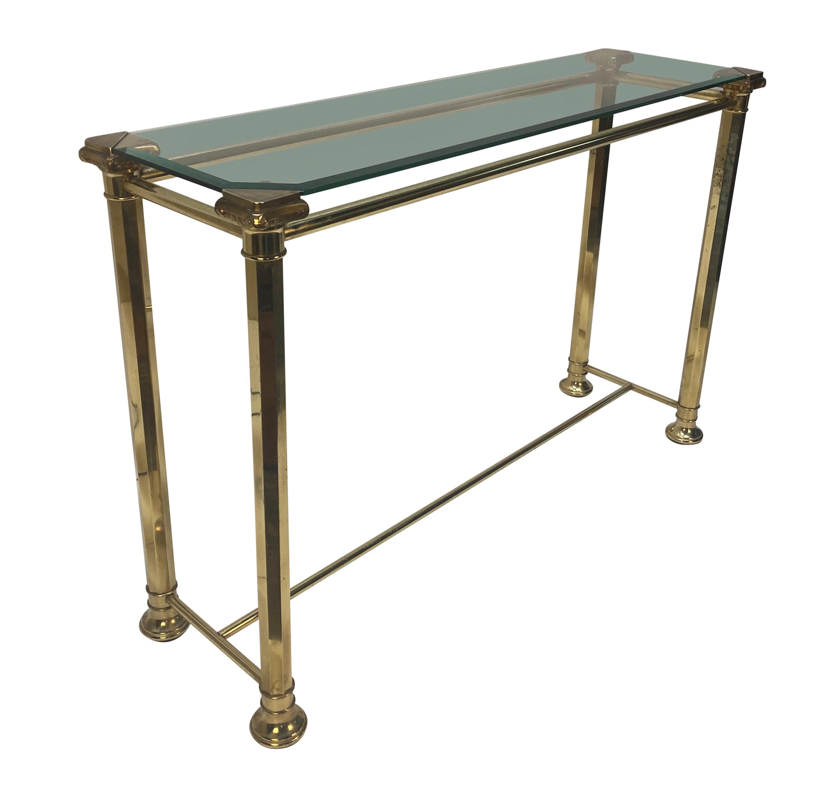 An Italian Mid-Century brass console table, with hexagonal legs capped with Ionic capitals, with an inset bevelled glass top.