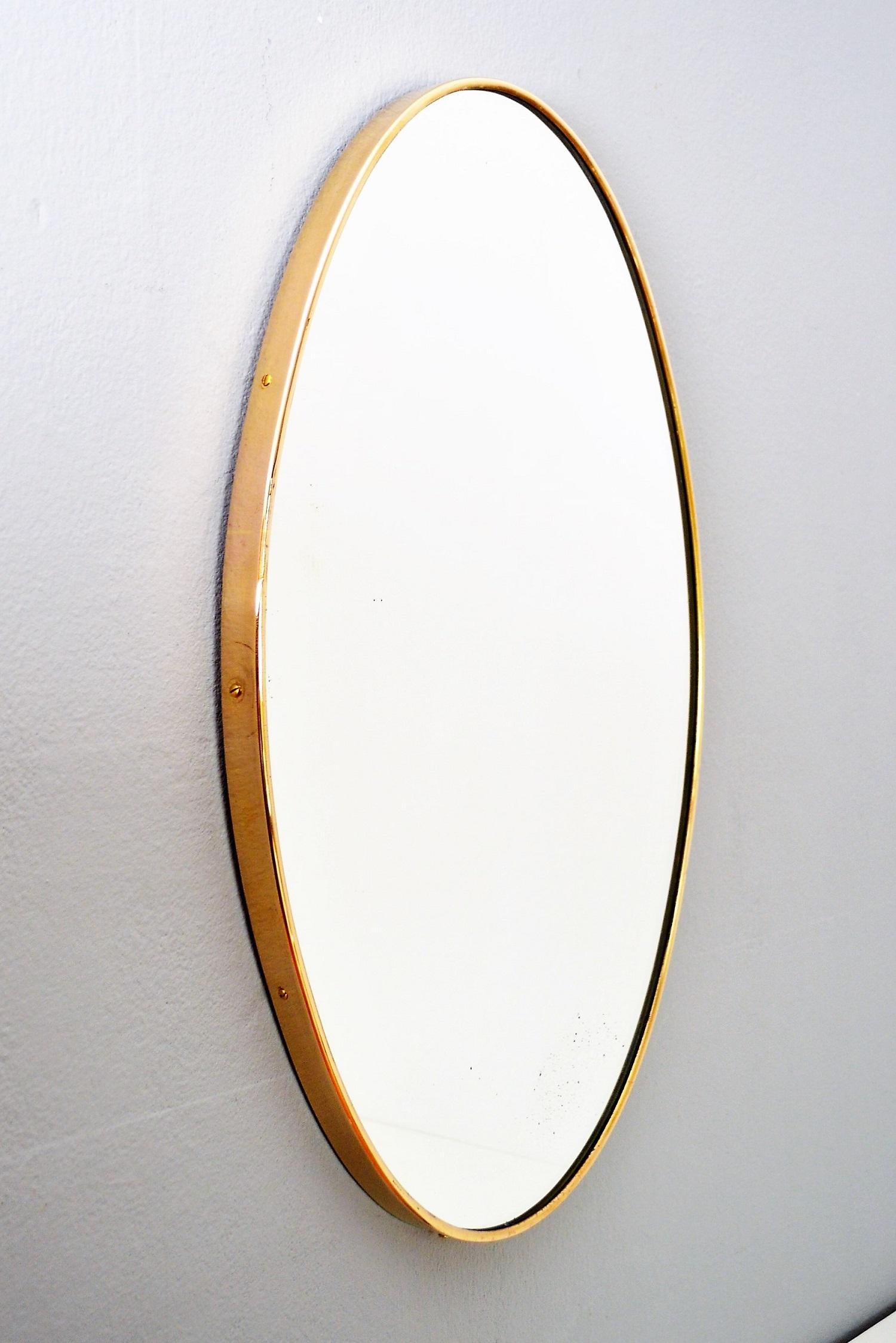 Beautiful small and heavy oval wall mirror with thick brass frame from Italian midcentury production.
The mirrored glass have been replaced with a new one and is therefore in excellent condition.
The mirror is equipped with strong wooden back