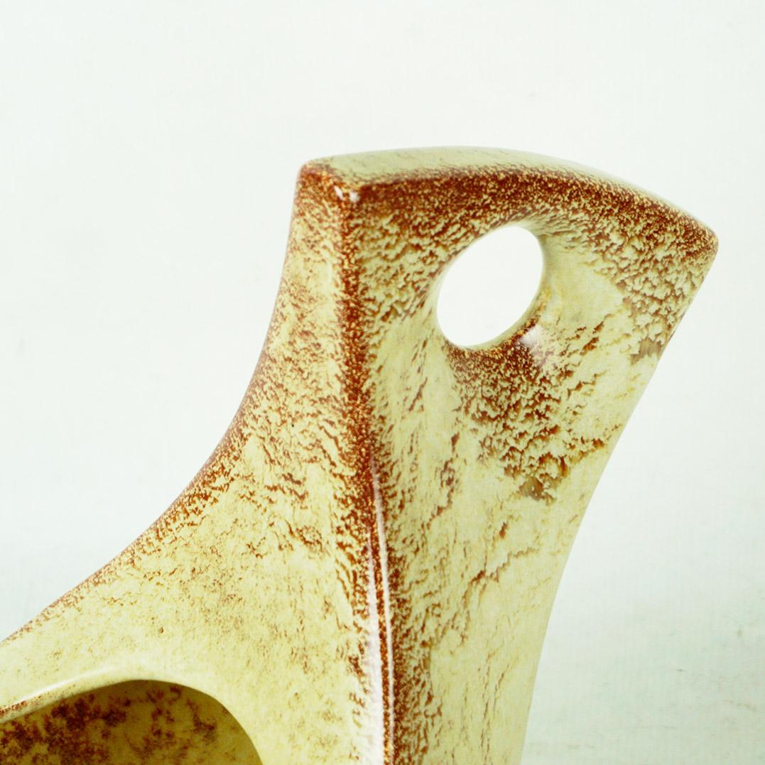 Questa fantastica brocca di grandi dimensioni in ceramica smaltata italiana è stata disegnata da Roberto Rigon per la ceramica d'arte Bertoncello intorno al 1970.
Presenta una bella smaltatura maculata in diverse tonalità di beige e marrone, con la