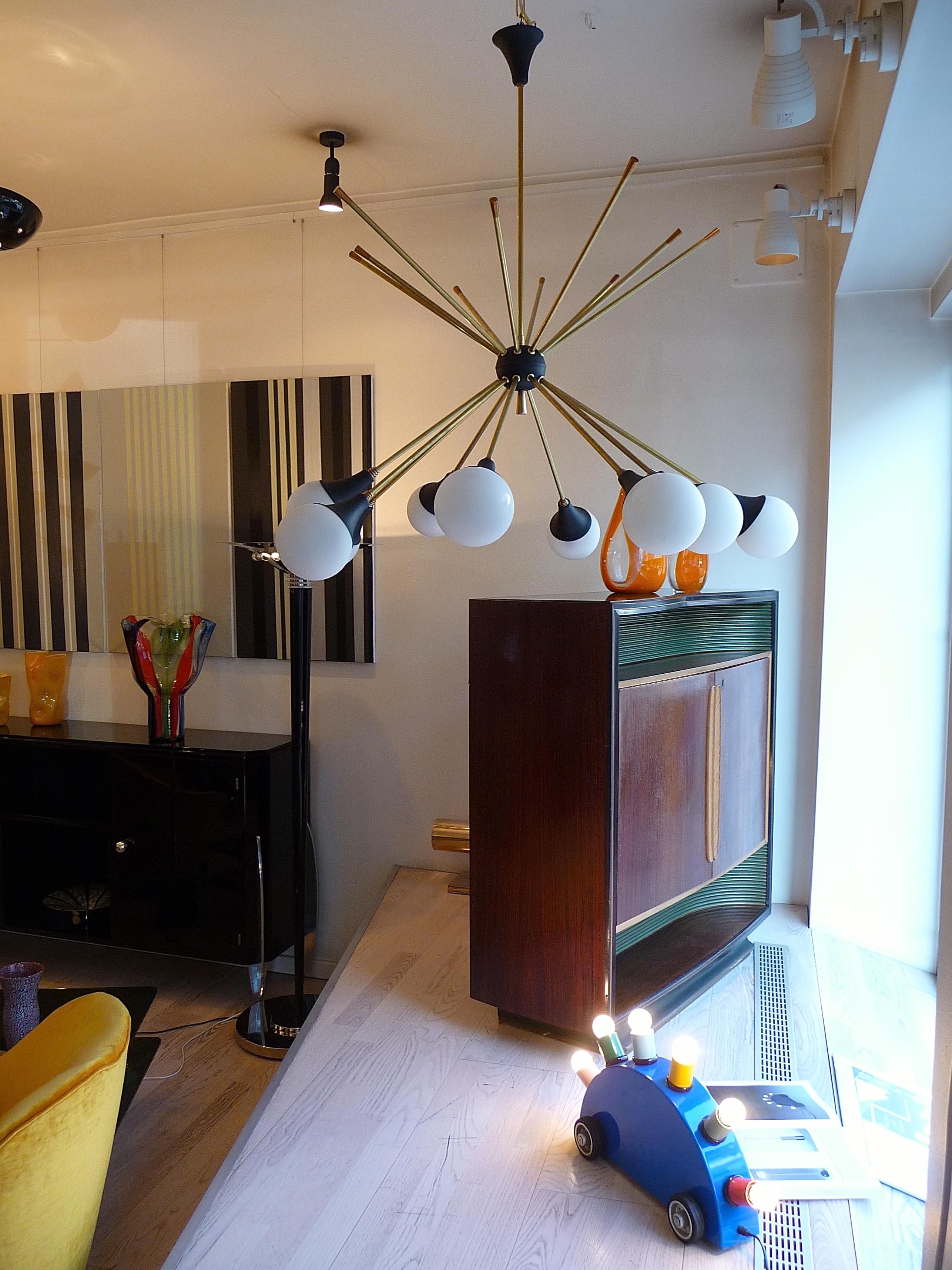 Lampadario italiano, stile Mid-Century Modern, 10 bracci, ognuno dei quali termina con un paralume in vetro.
Elegante lampadario a dieci bracci in ottone, metallo verniciato e paralumi in vetro opalino. Per gli Stati Uniti, le consegneremo con basi
