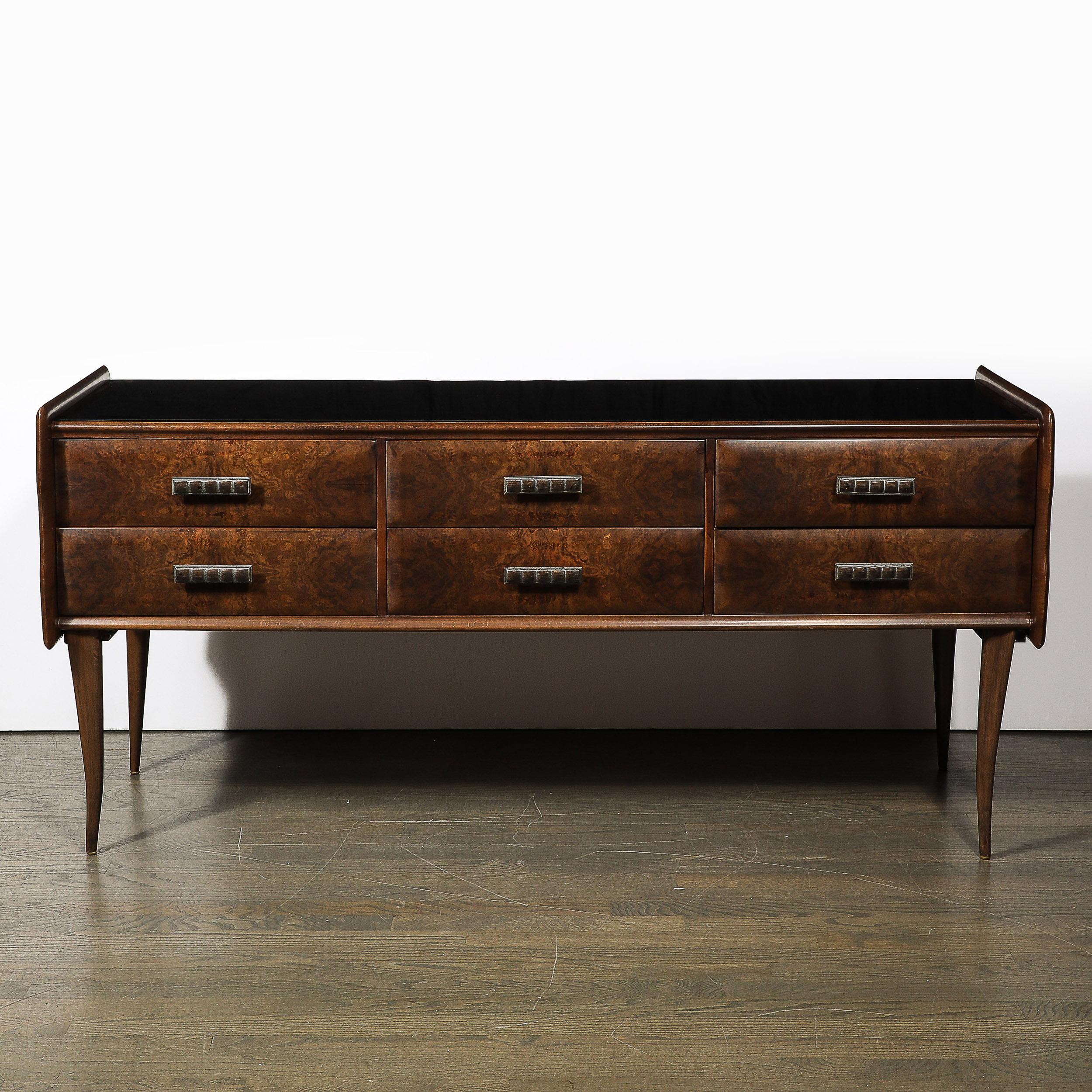 This stunning Mid-Century Modern chest was realized, in the Manner of Gio Ponti, in Italy, circa 1950. It has been handcrafted in burled and hand rubbed book matched walnut, with stylized pulls and a black vitrolite top. No aesthetic detail was