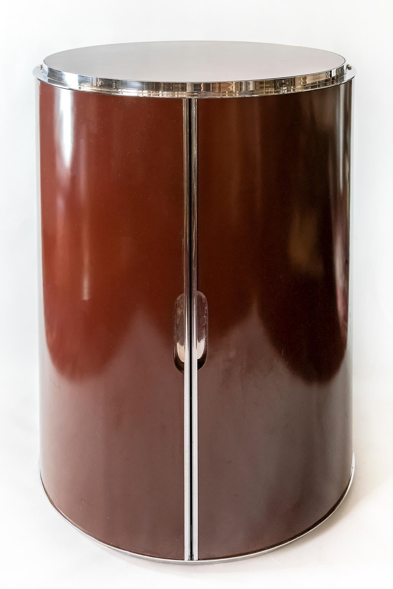 Italian midcentury circular bar cabinet with two glass shelves inside.
The bar in on wheels. It's body is made of burgundy colored plywood decorated with metal details.