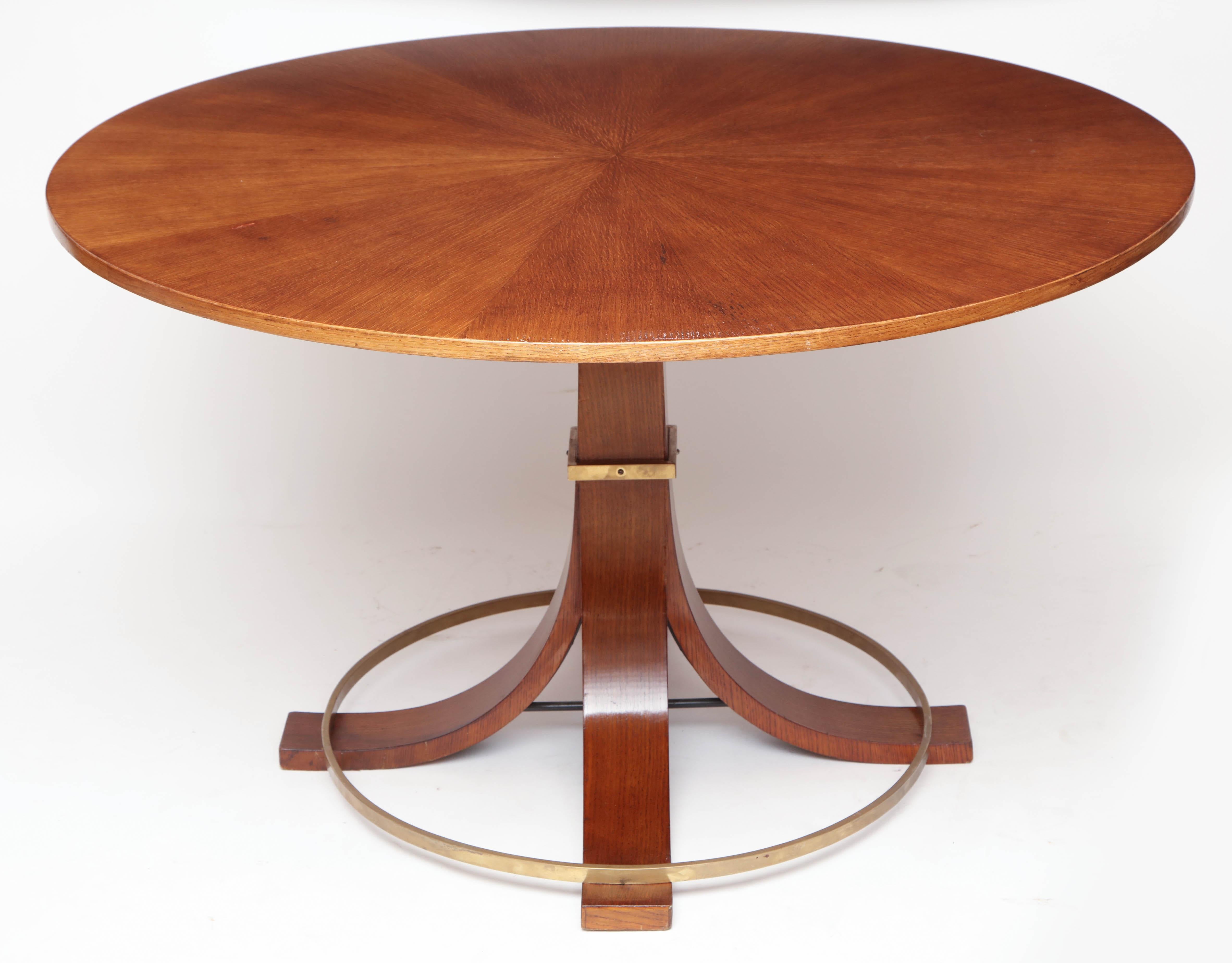 Round oak table with centre pedestal ending in flared legs and circular brass stretcher, Italy, circa 1950.

Overall dimensions: 51”D, 30.5” H

Available to see in our NYC Showroom 
BK Antiques
306 East 61st St. 2nd fl.
New York, NY 10065