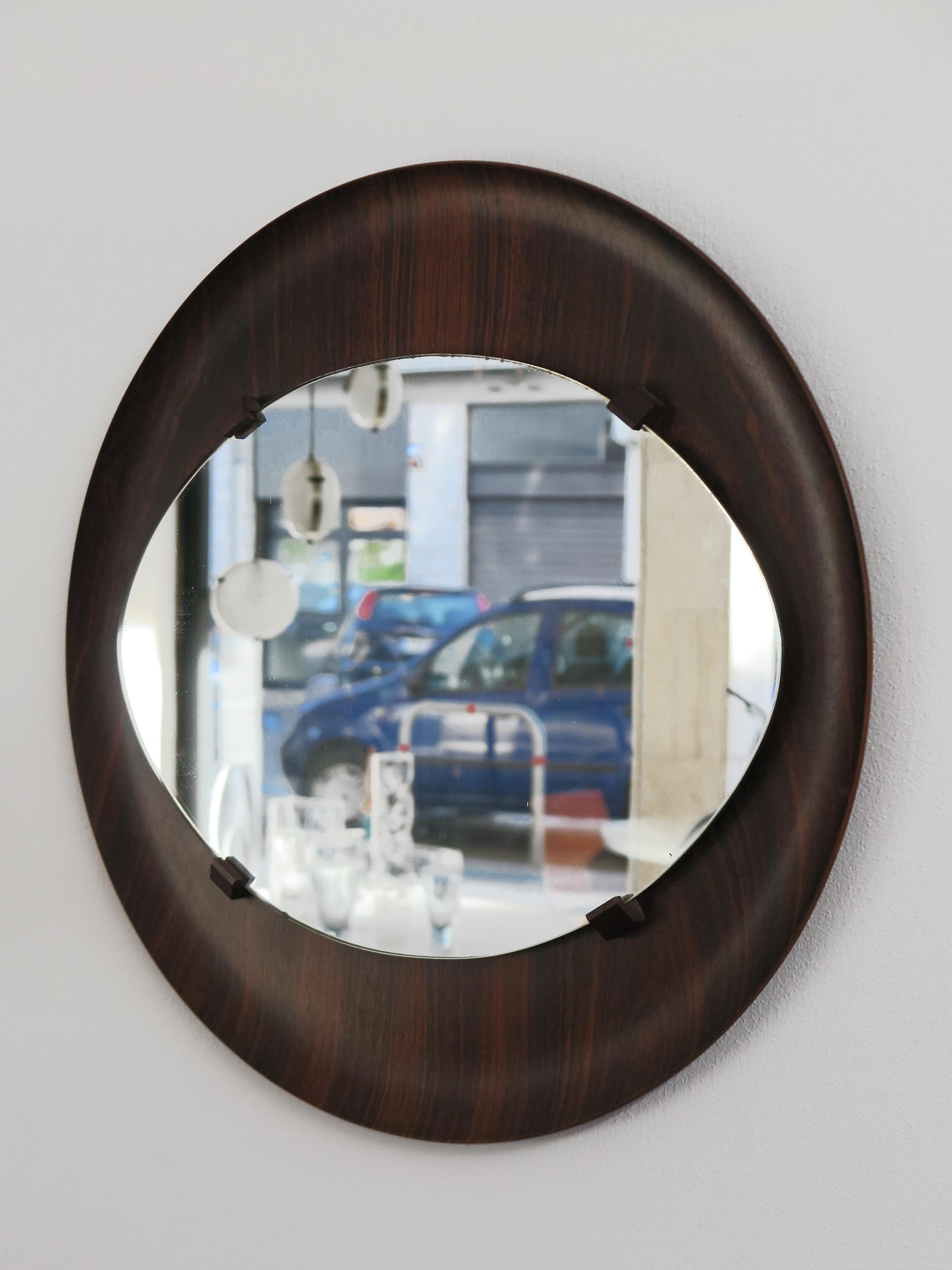 Italian midcentury wall mirror with circular frame in curved dark wood and mirrored glass, 1960s

Please note that the item is original of the period and this shows normal signs of age and use.