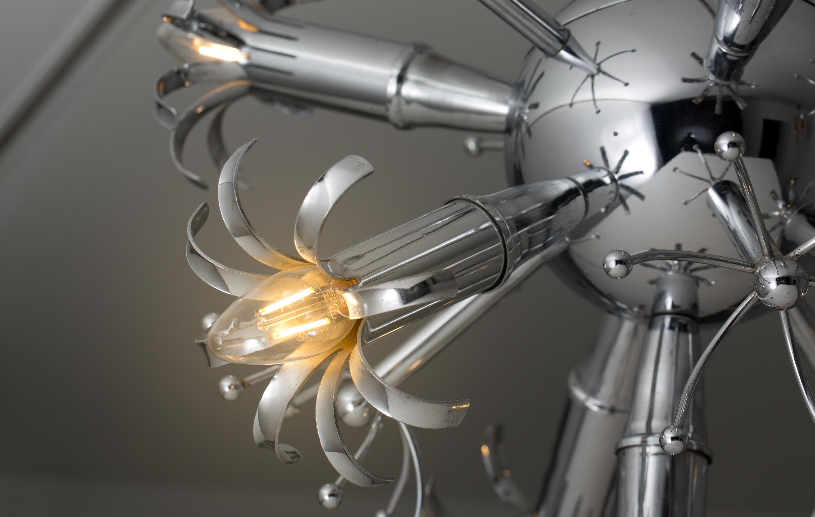 This futurism Italian midcentury design chandelier was produced during the 1950s. The chandelier is made from nickel-plated metal and has six arms with light bulbs at the end. The midcentury design light has a metal ball as a base. The light bulbs