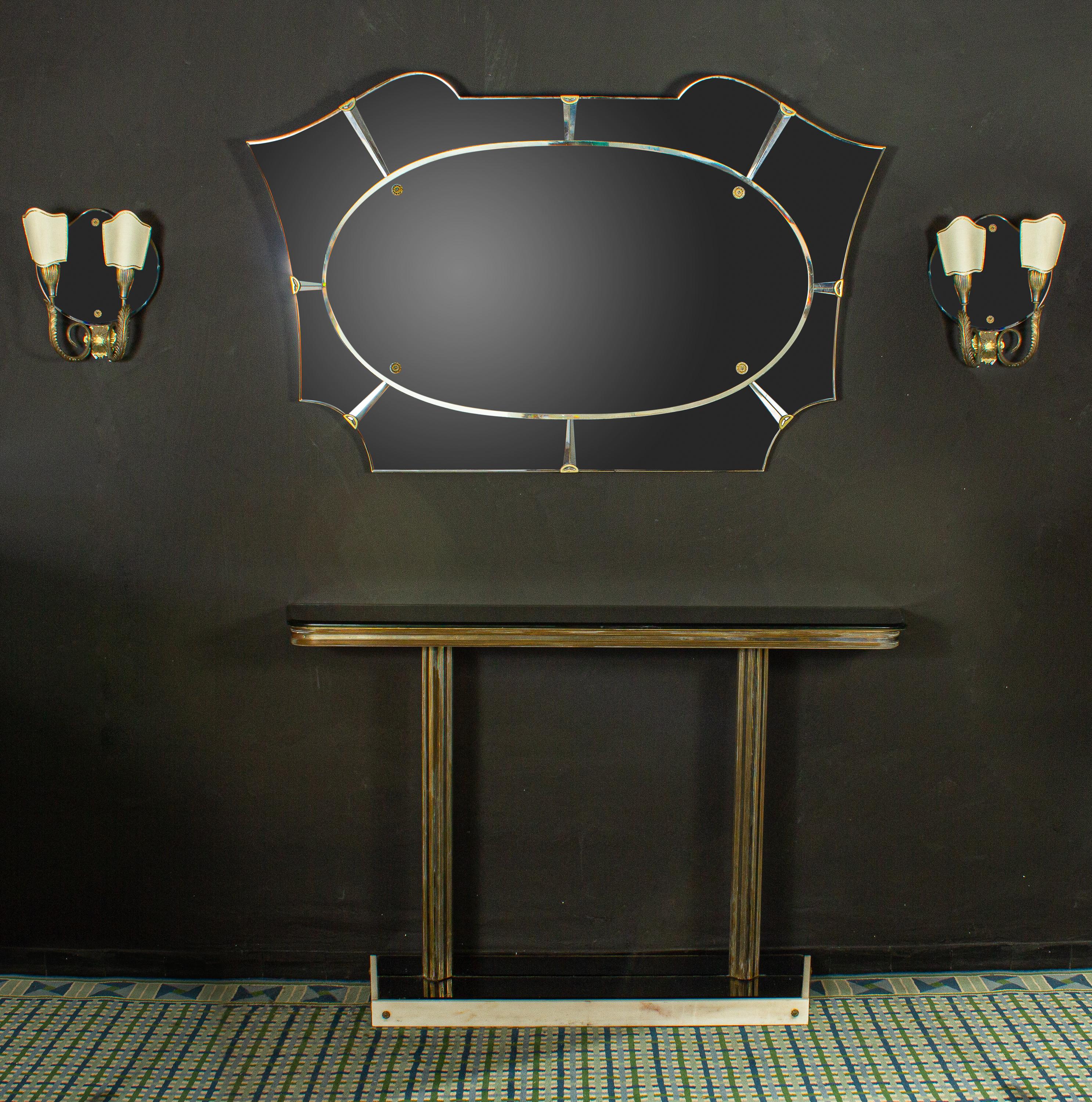 Italian midcentury design brass console table with a fume mirror top and a white marble finished base .
the set include the Mirror and a pair of brass mounted Sconces.
Elegant solution for an entrance or a dining room.
Measurements:
Console