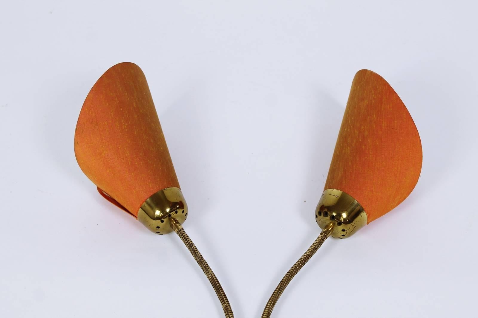  Stunning Mid century brass wall lamp produced in Italy in the 1950s. Has a brass base and two adjustable gooseneck arms.
Shades are made of orange fabric in good vintage condition
.
 