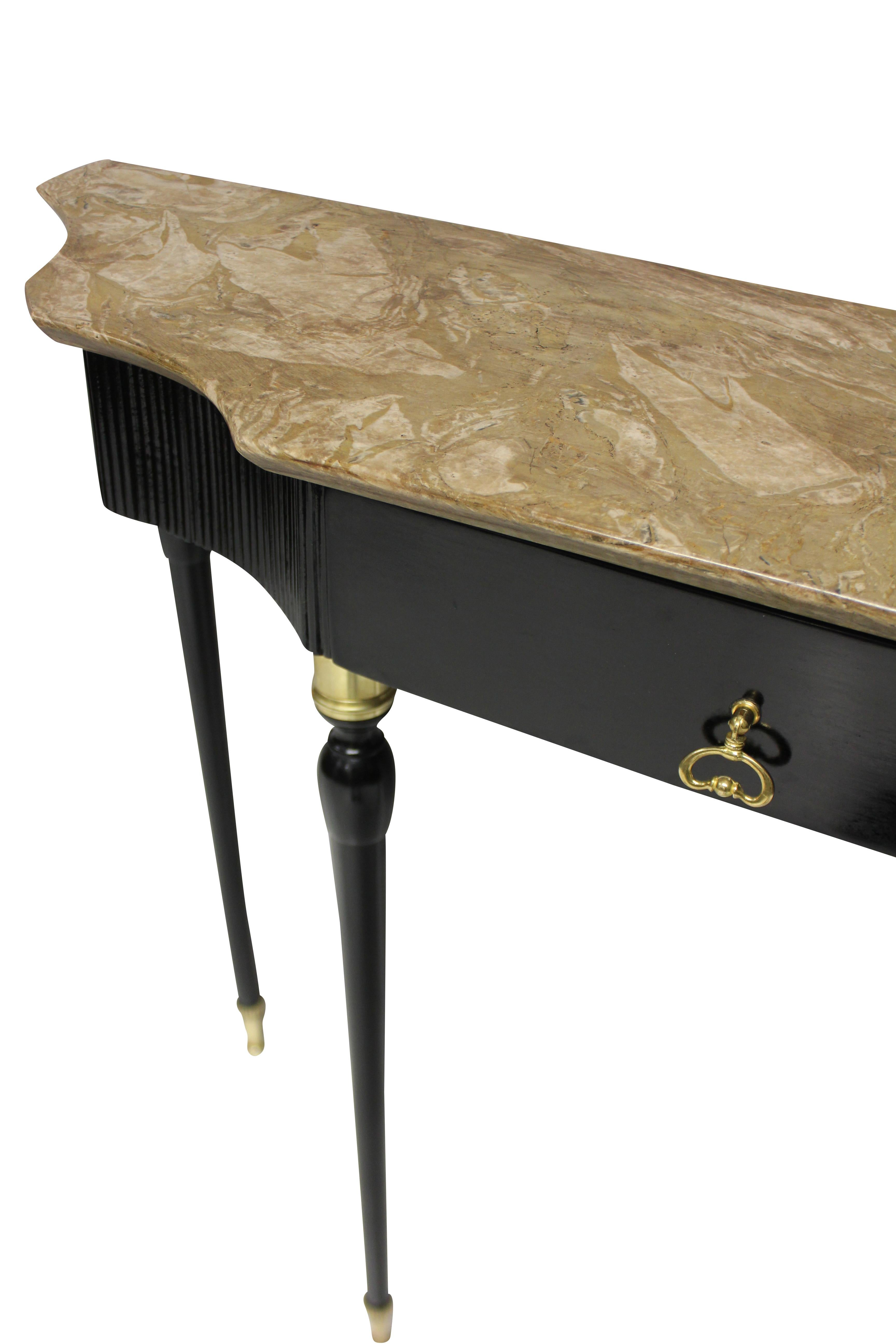 A stylish Italian midcentury ebonized console table, with brass sabot feet and decoration. The ribbed frieze with a single drawer and a shaped faun fossil marble top.