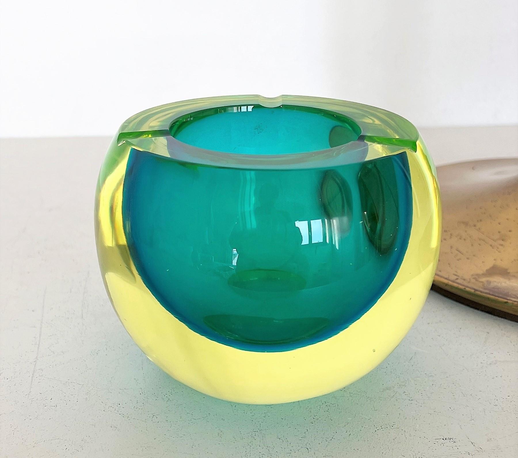 Gorgeous floor standing Ashtray made of strong heavy Brass Base and beautiful Murano sommerso Glass Bowl. 
The hand-crafted Murano bowl is made of different submerged green shiny colors, typically for Murano glass quality. 
Depending on the light,