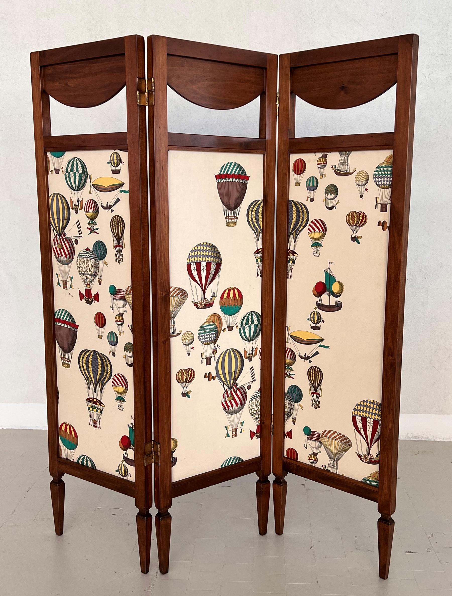 Gorgeous folding screen or room divider composed of three parts.
Made in Italy on the 1990s.
Made of solid chestnut wood in excellent quality and refined on one side with Fornasetti fabric.
The back side of the screen is in full chestnut