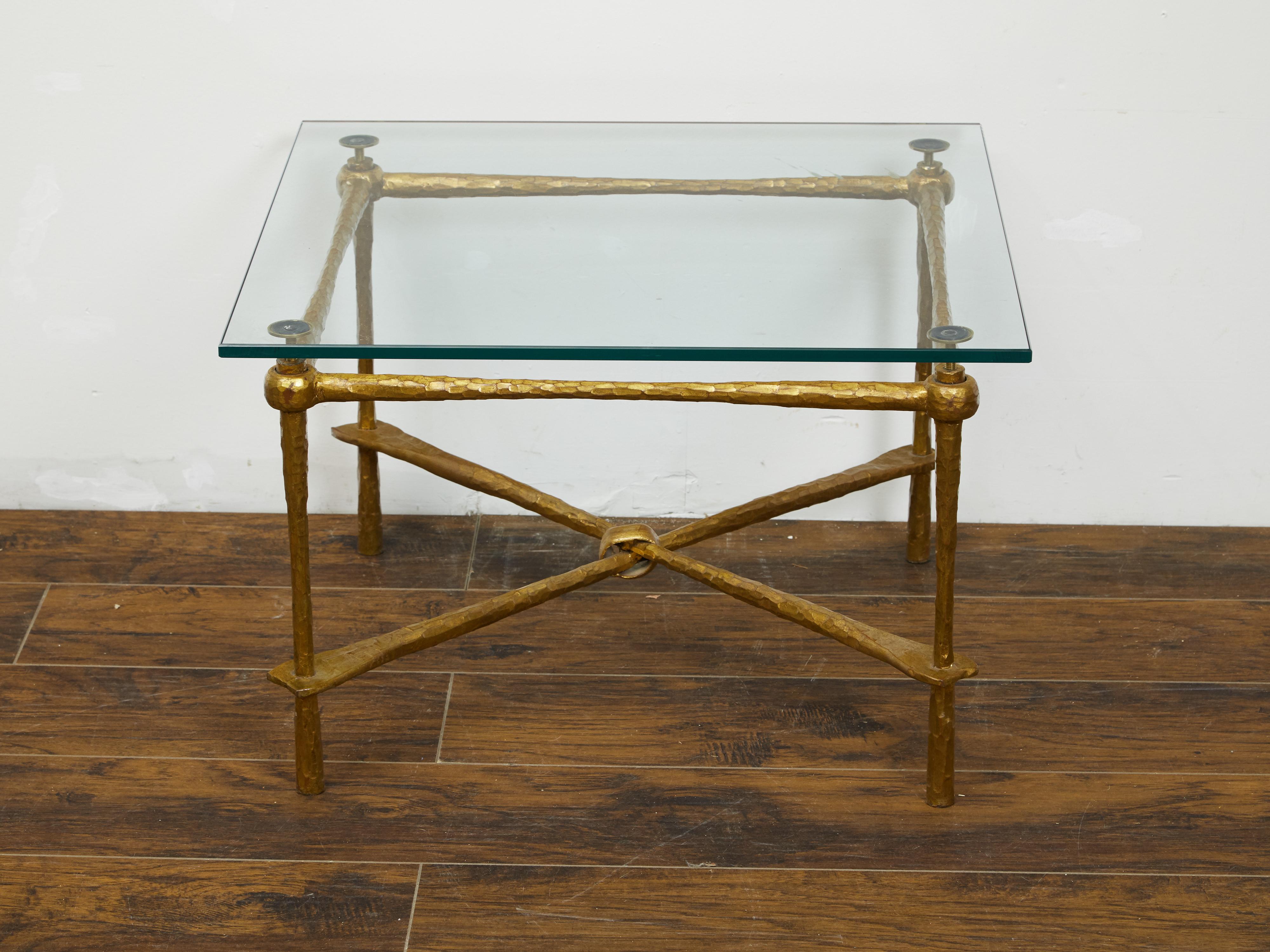 An Italian gilt metal coffee table from the mid 20th century, with glass top and hammered style accents. Created in Italy during the midcentury period, this gilt metal table features a square glass top sitting above a gilt metal base with hammered