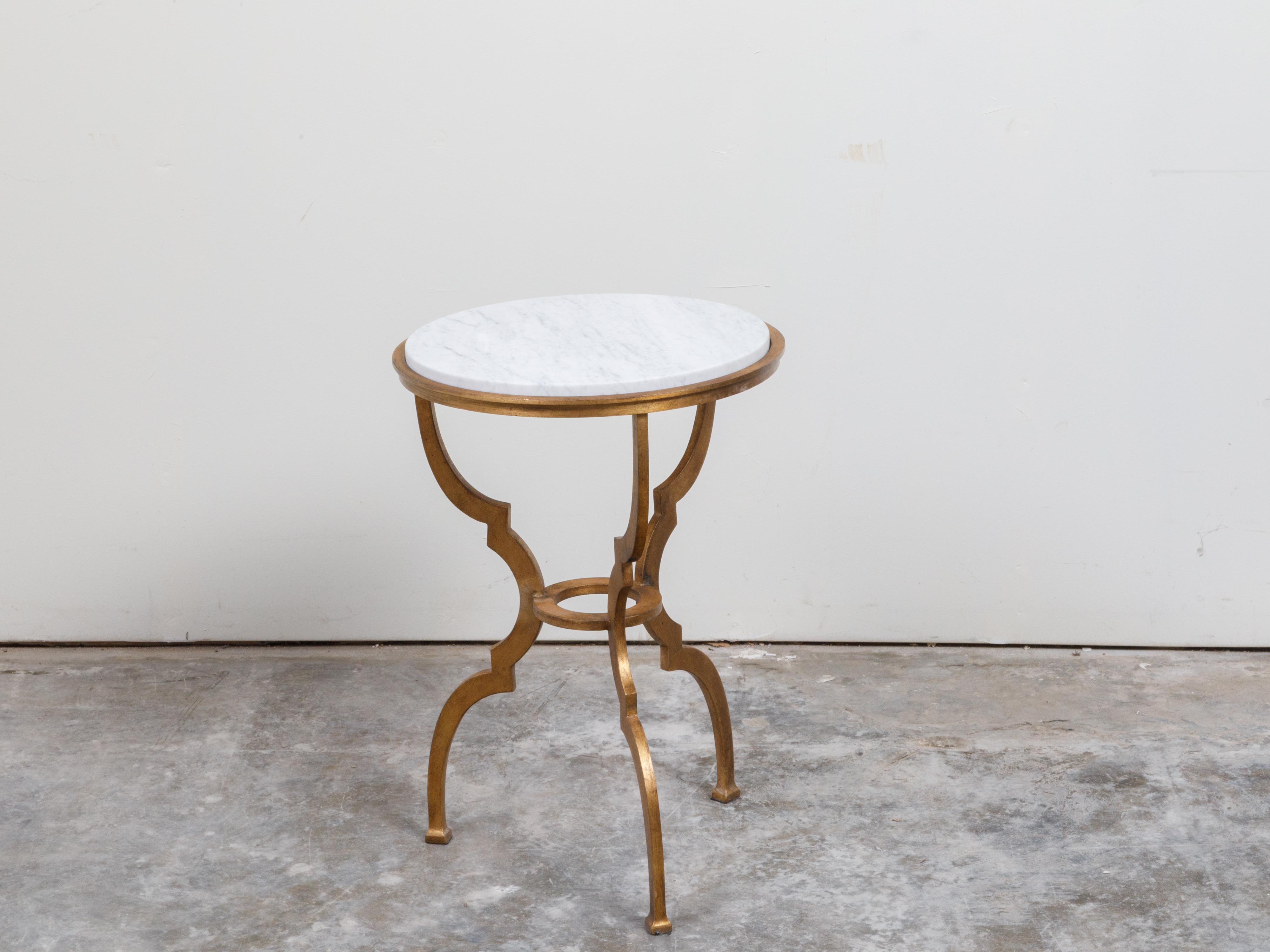 An Italian gilt metal side table from the mid 20th century, with white marble top and scrolling legs. Created in England during the midcentury period, this side table features a circular white veined marble top sitting above three scrolling legs