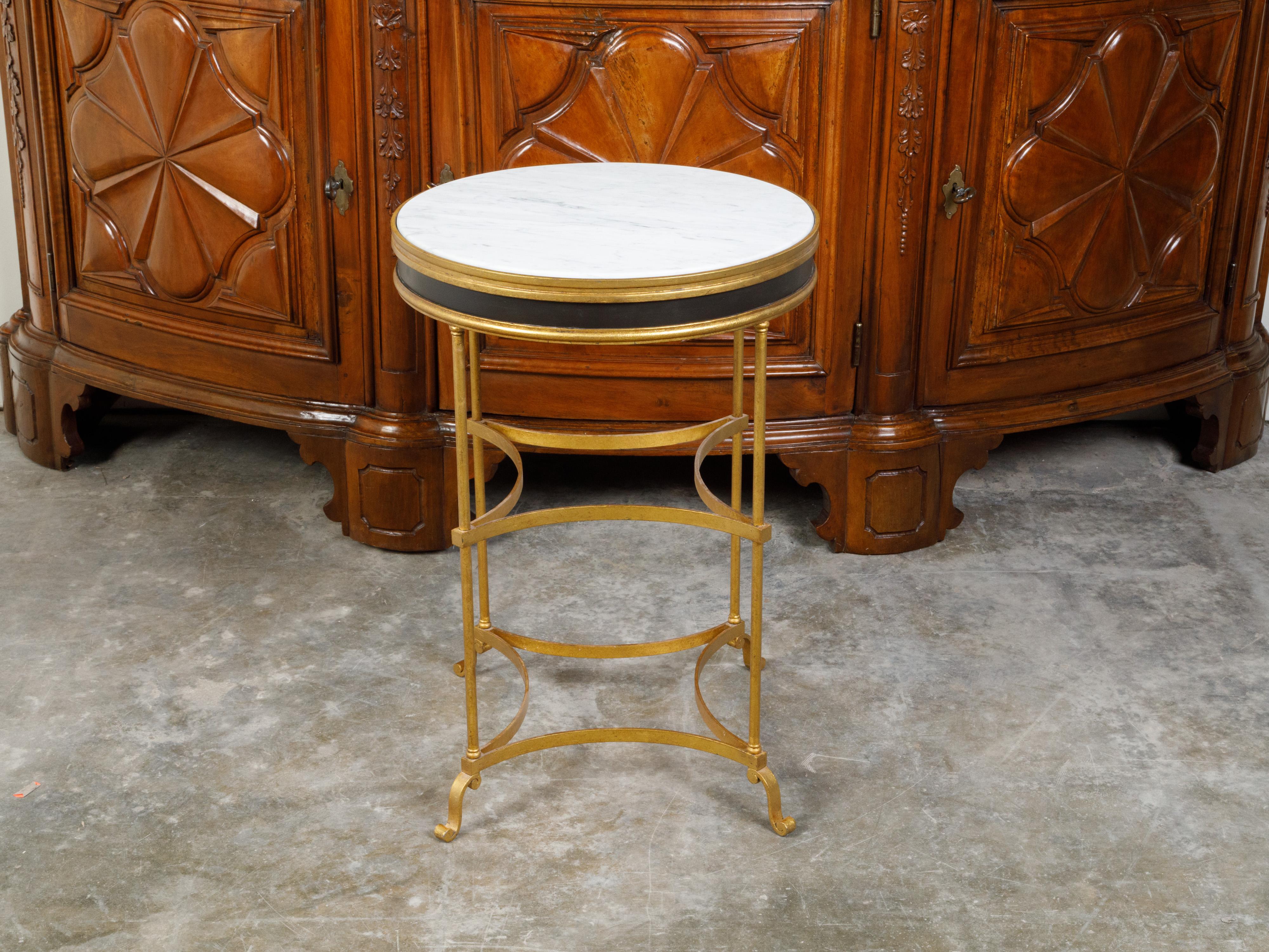 An Italian gilt metal side table from the mid 20th century, with white marble top and in-curving accents. Created in Italy during the Midcentury period, this side table features a circular white marble top secured within a gilt metal apron
