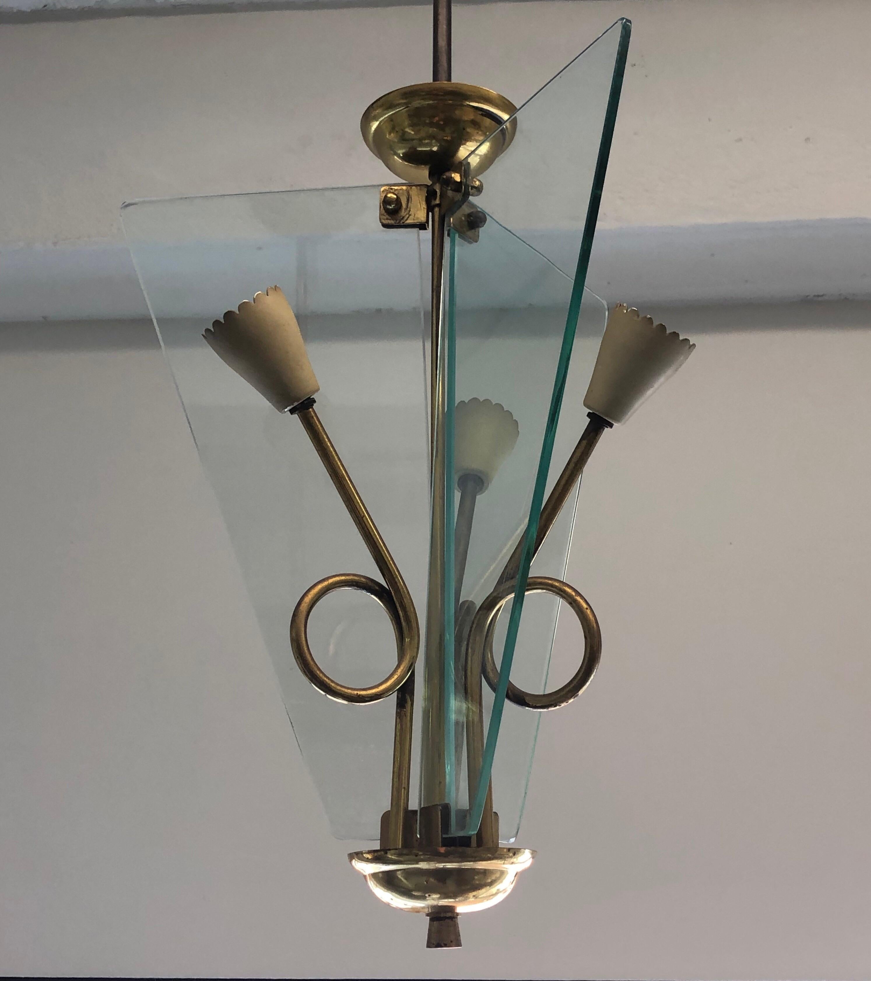 Stylish Italian Mid-Century Modern green glass pendant, lantern by Luigi Fontana.

The fixture is divided into 3 triangular glass sections. Each section features a single brass stem in a twist pattern ending in white enameled bobeche holding a