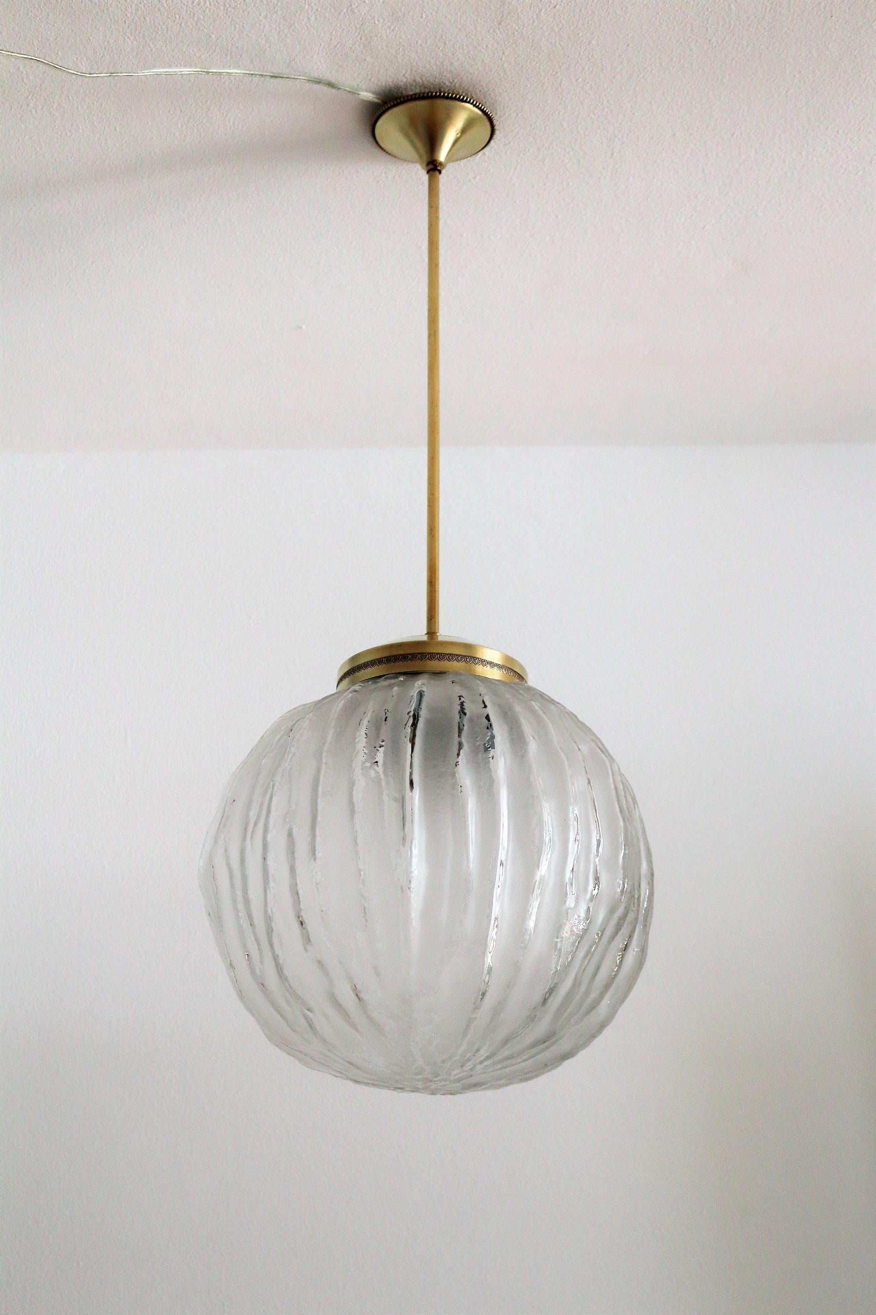 Beautiful Italian midcentury chandelier with particular Murano art glass and brass details.
The glass globe has an irregular, organic shape with satinated and shiny glass parts.
Leaves nice shadows on near wall and ceiling.
The same glass have