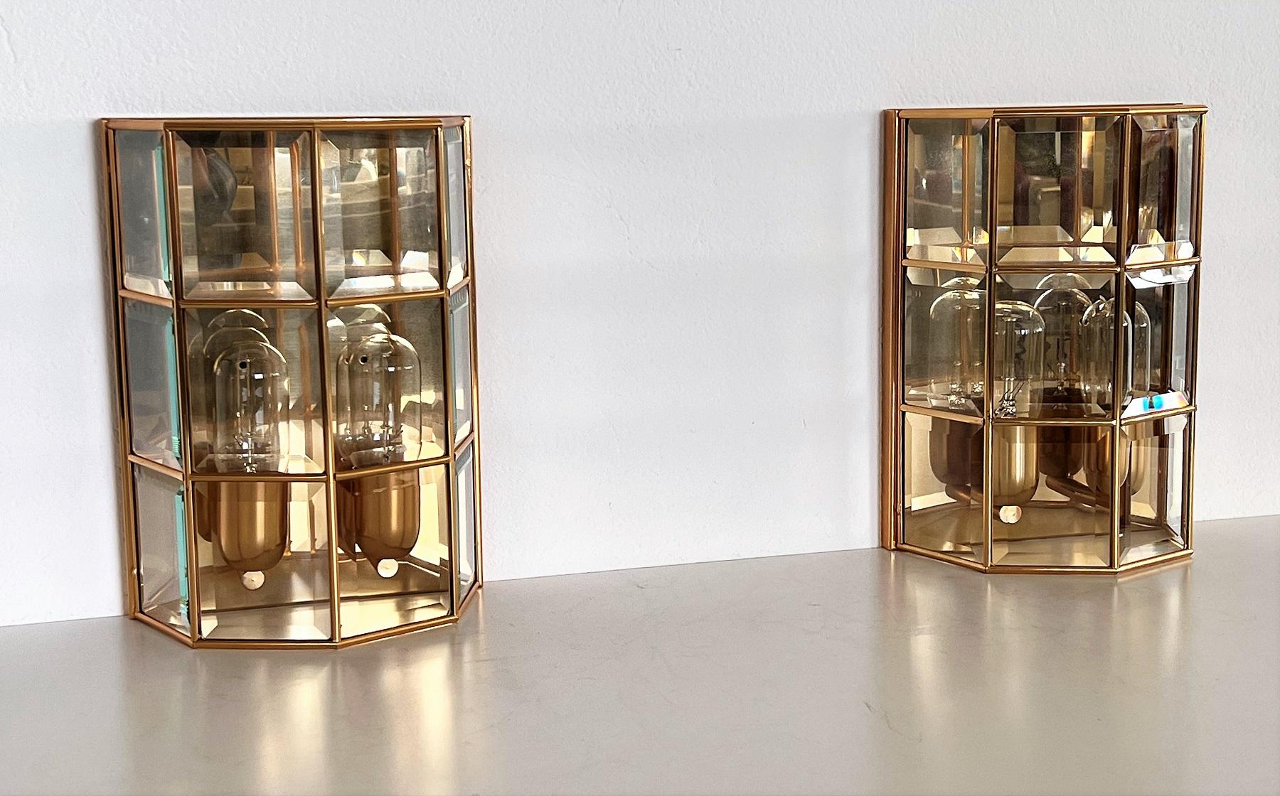 Gorgeous and shiny pair of wall sconces Made in Italy of great craftsmanship.
The single glass pieces have all cut at the edges, which gives them a gorgeous shiny effect in the elegant Hollywood Regency style.
They are mounted on a metal frame