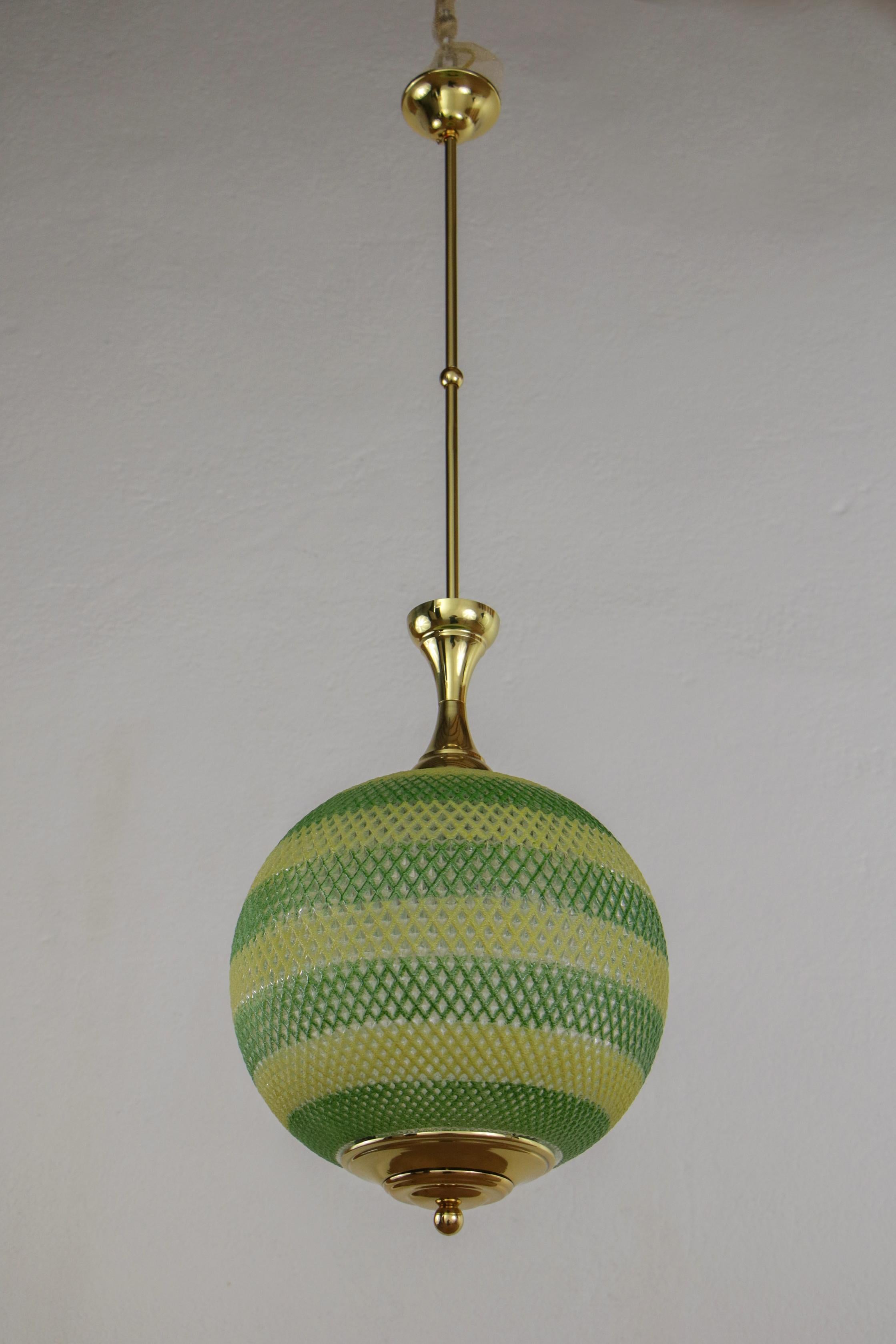 This Italian chandelier from the 1960s is a unique piece with a great decorative impact. It is made of yellow and green glass and shiny transparent lacquered brass. The glass parts are worked in relief and show a great quality of execution. The