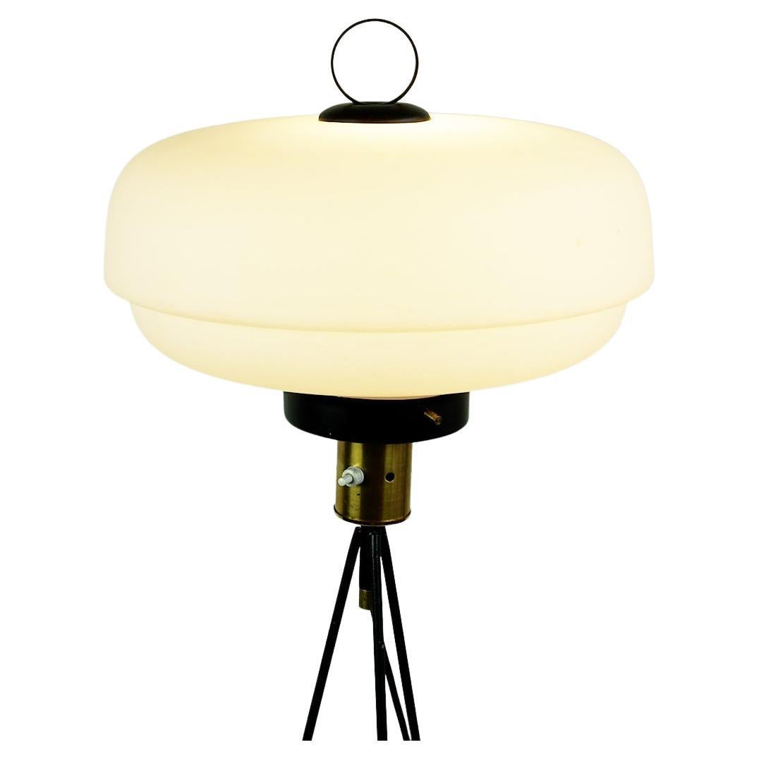Ce charmant et élégant lampadaire italien du milieu du siècle a été fabriqué dans les années 1950 et...  se caractérise par une base tripode laquée noire avec des détails en laiton et un abat-jour en verre opalin blanc. Il est en très bon état, en
