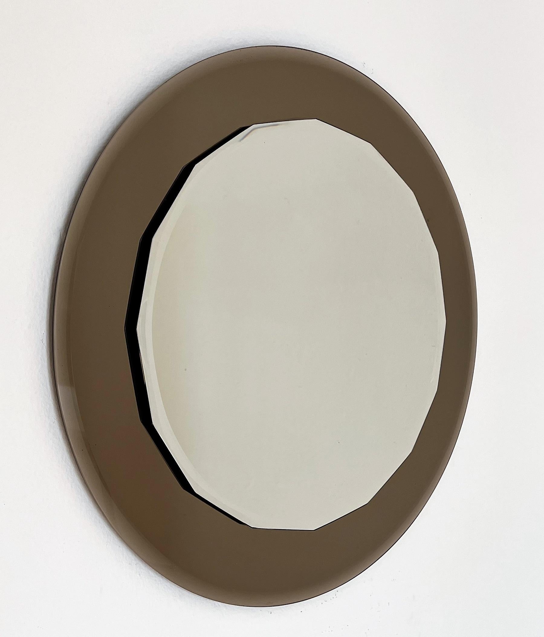 Round wall mirror made of heavy crystal mirrored glasses, Made in Italy by Cristal Arte during the 1970s.
The mirror is made of two mirror plates, the bigger round one behind is in light brown (smoke) color.
The smaller mirror on top has beautifully