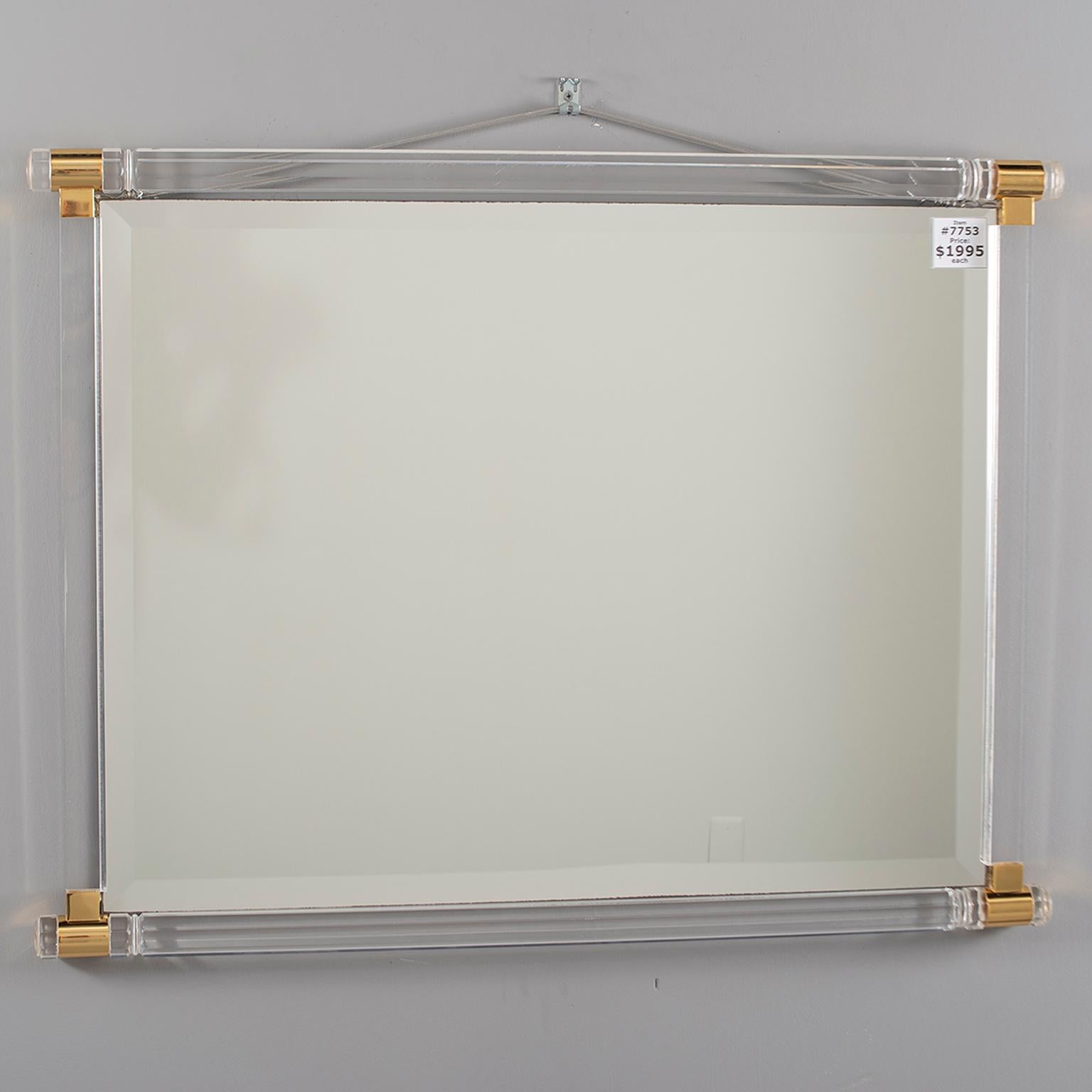 Italian wall mirror has a thick clear Lucite frame with polished brass accents. Mirror has bevelled edges. Excellent overall condition, circa 1970s.
