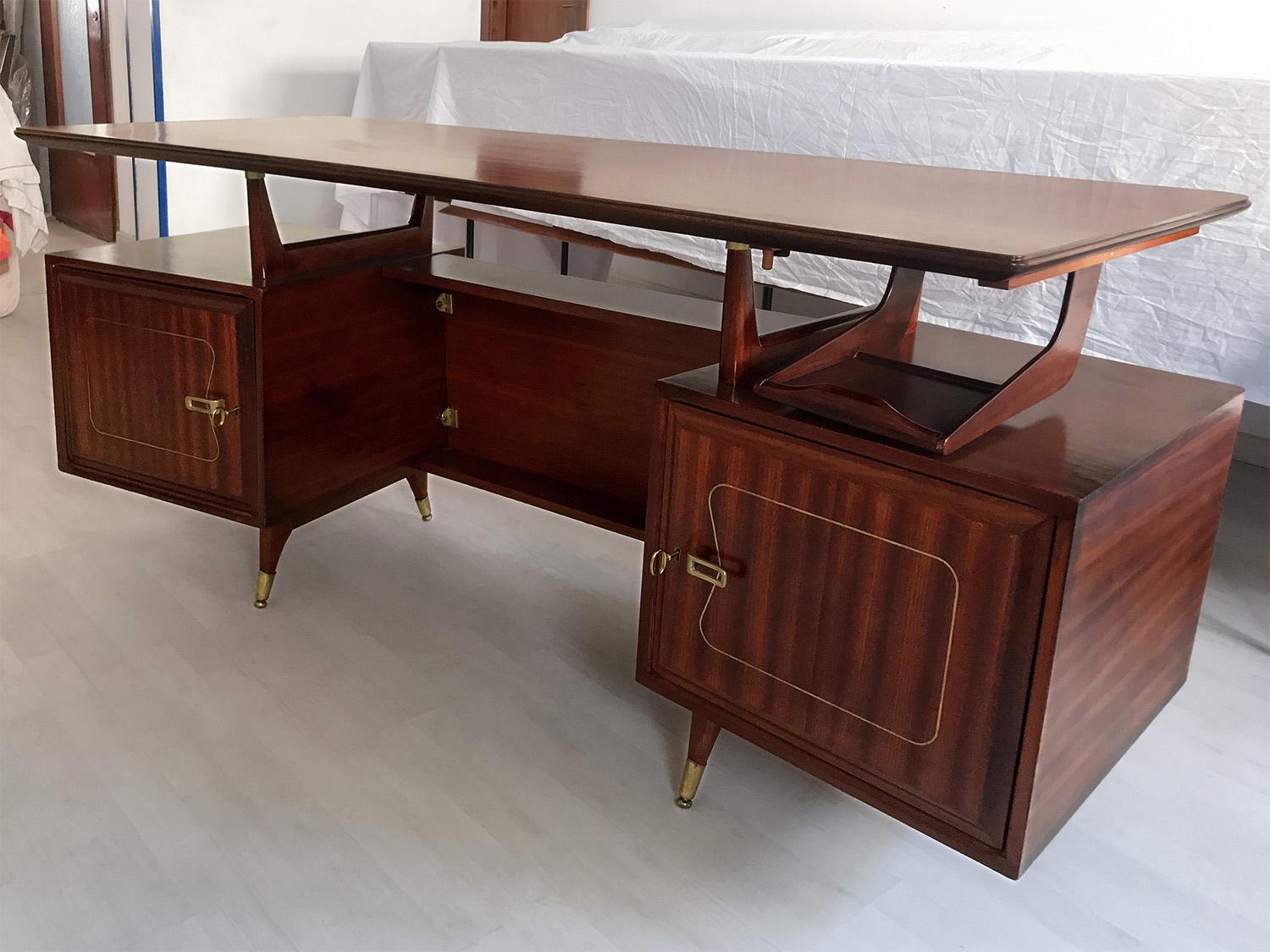 Amazing and unique design for this Italian executive Desk of the 1950s, attributed to La Permanente Mobili Cantù, with the structure in mahogany wood veneer finished with brass details.
The side compartments are lockable and opening the doors reveal
