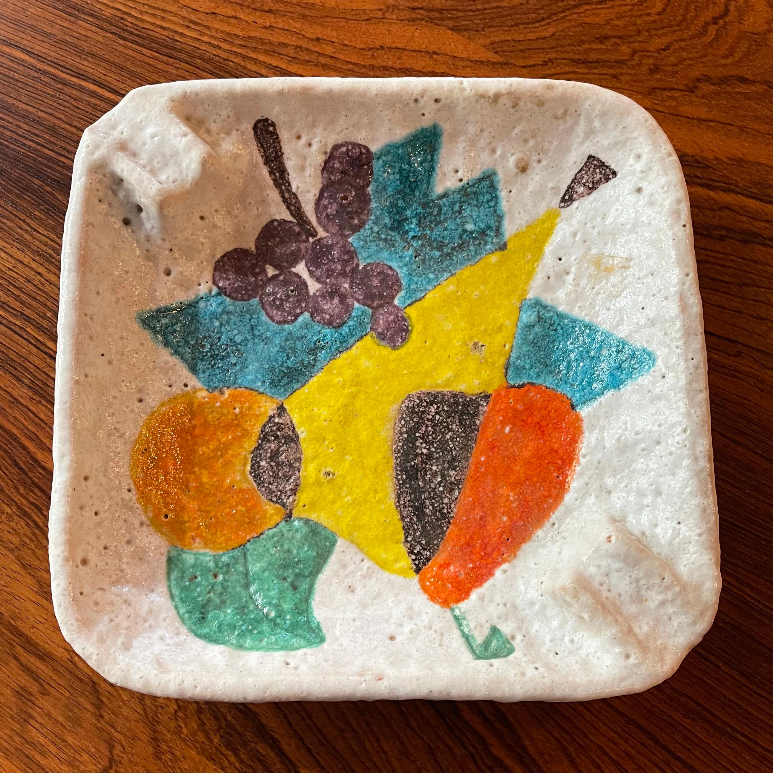 Large, Italian, midcentury modern, art pottery ashtray by Raymor features a painted, multicolor, abstract fruit arrangement. The tray has a lava glaze technique which gives the surface a smooth yet irregular texture. The tray feels weighty with the